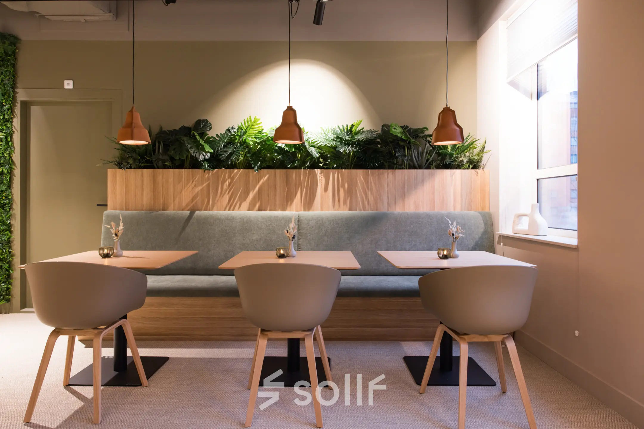 Een modern ingerichte werkruimte in een kantoorpand op Hullenbergweg 109-135, Amsterdam Zuid-Oost, met stijlvolle stoelen en tafels, omgeven door groene planten. Ideaal voor kantoorruimte huren.