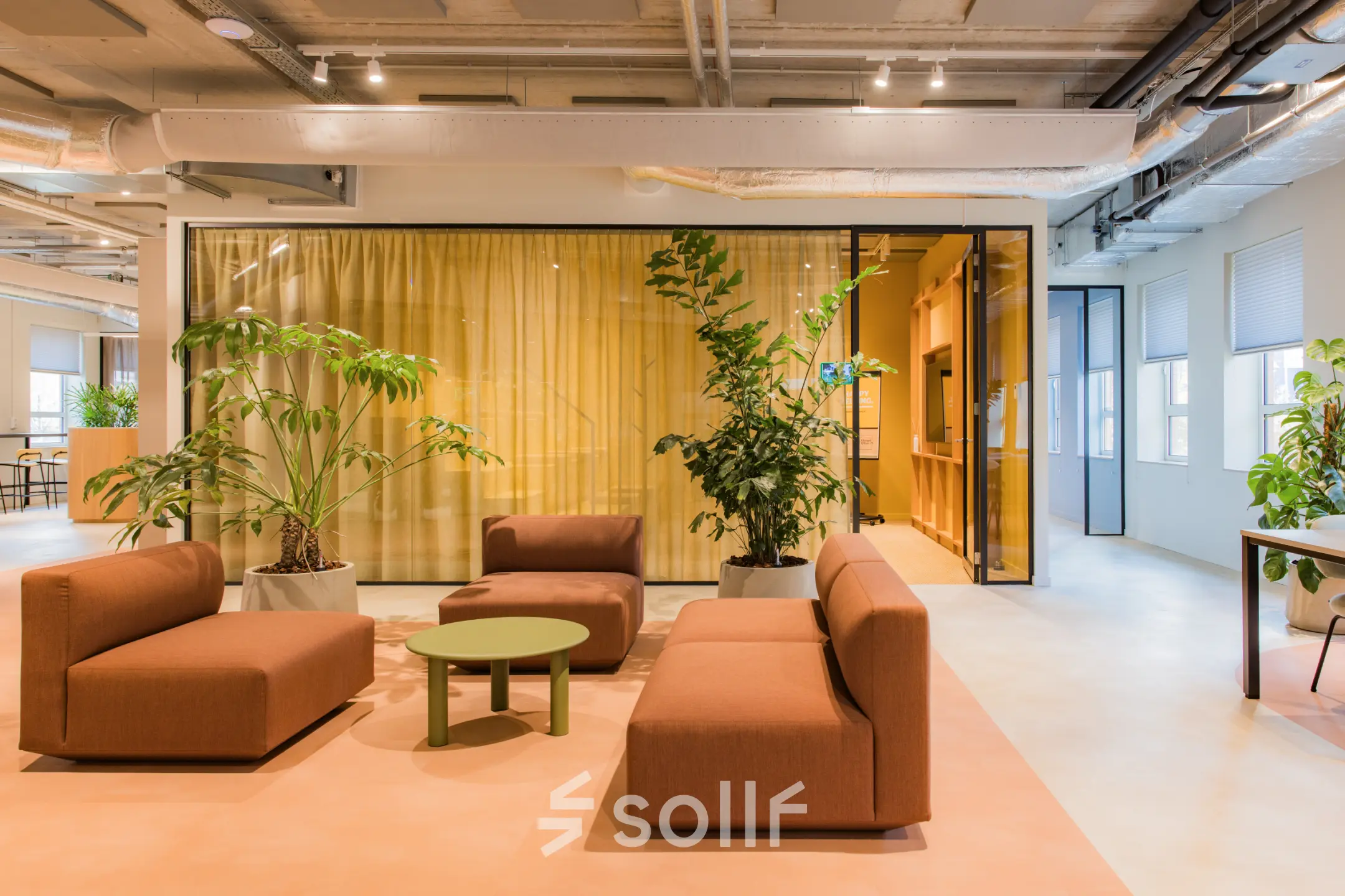 Moderne kantoorruimte in Amsterdam Zuid-Oost met stijlvolle zitbanken en groene planten, ideaal om te huren voor creatieve brainstormsessies.