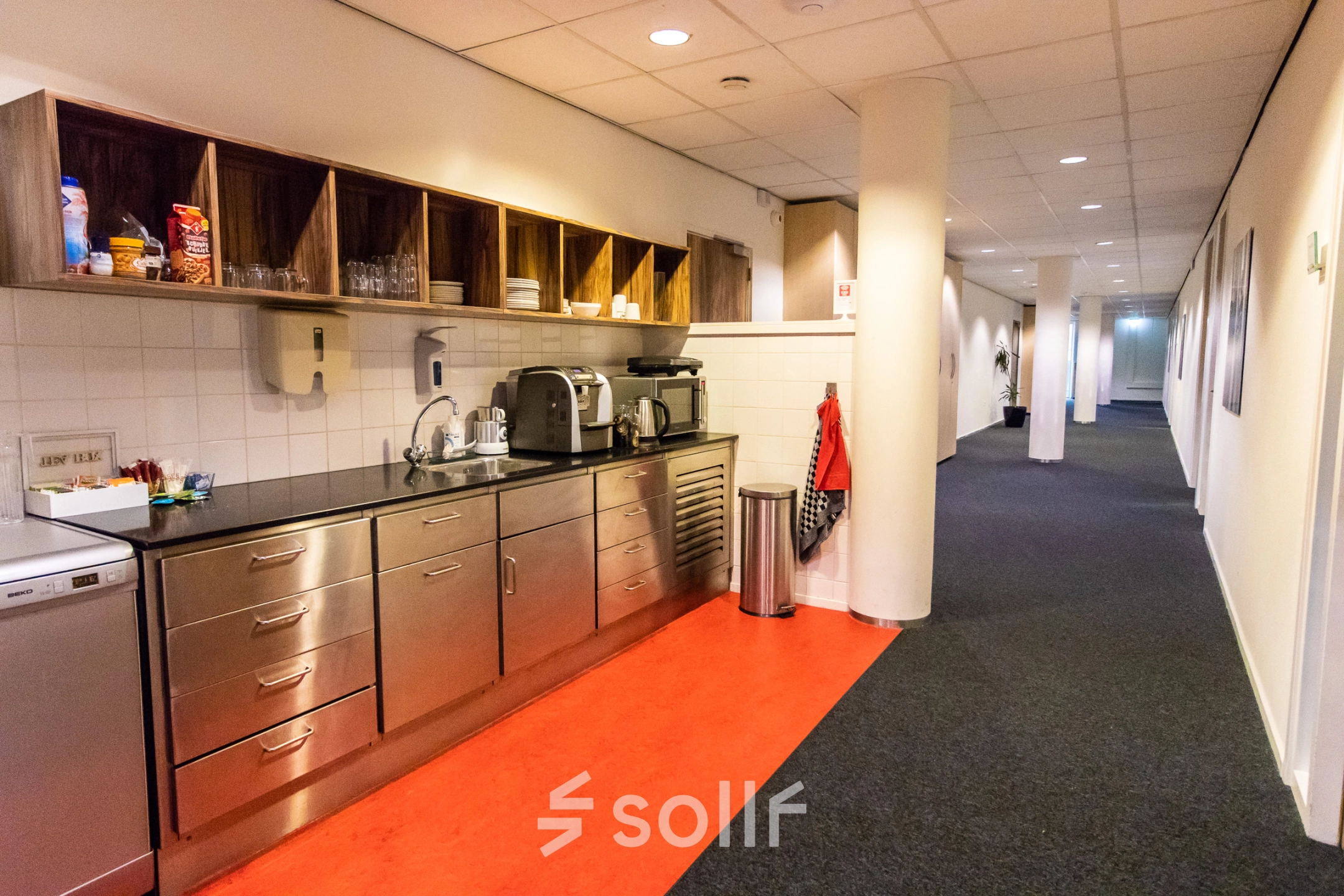 Koffiepauzehoek in kantoorpand op Hullenbergweg 278, met roestvrijstalen aanrecht en open houten schappen, gelegen in Amsterdam Zuid-Oost.
