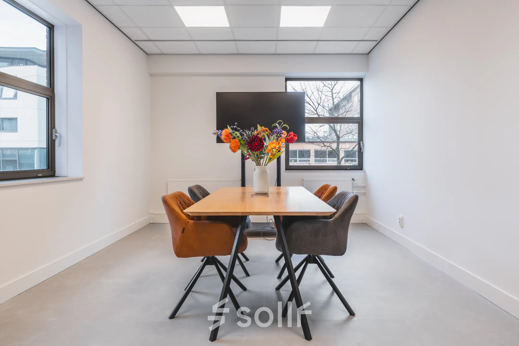 Vergaderruimte in kantoorpand aan Paasheuvelweg 20, Amsterdam Zuid-Oost, met houten tafel en kleurrijke bloemen. Kantoorruimte huren in een moderne setting.