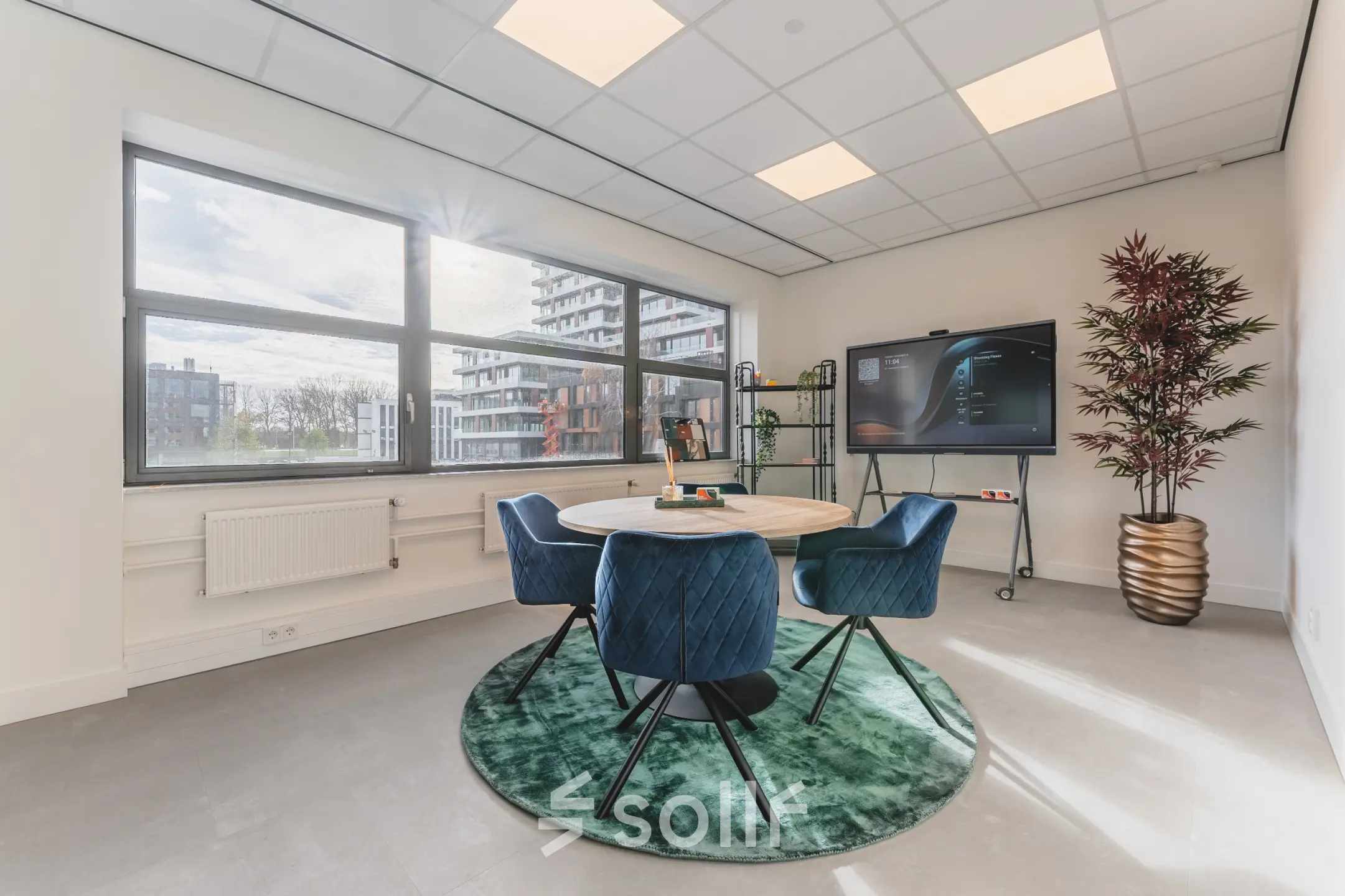 Moderne en lichte kantoorruimte op Paasheuvelweg 20 in Amsterdam Zuid-Oost met grote ramen, een ronde tafel met vier stoelen, een display en planten. Ideaal voor kantoorruimte huren.