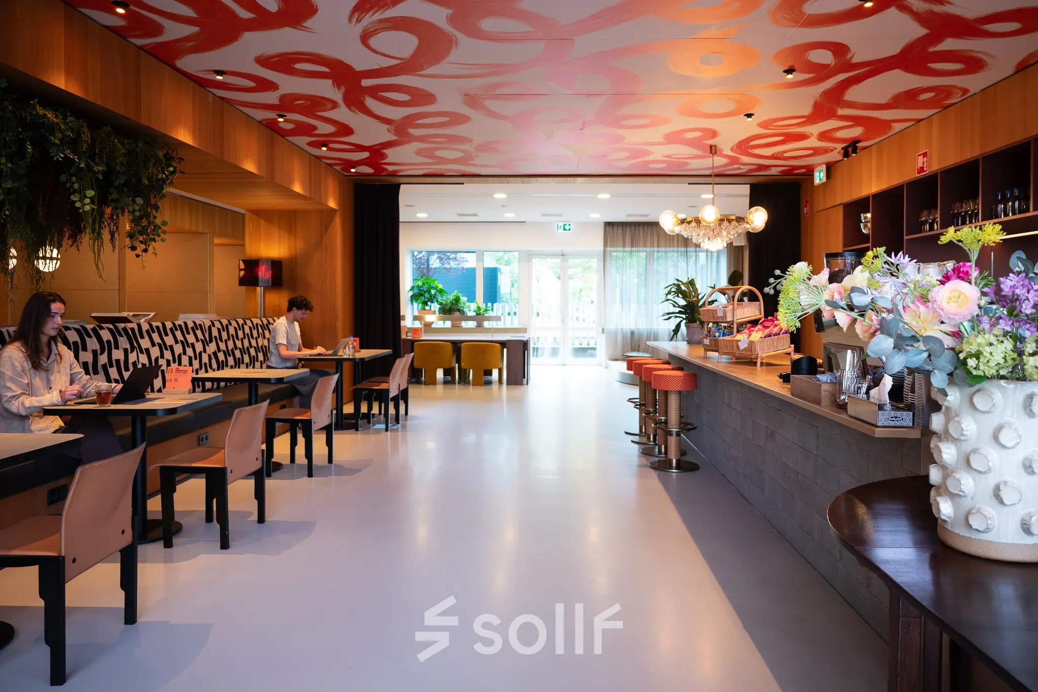 Stijlvolle kantoorruimte huren met kleurrijke accenten op Barbara Strozzilaan 101, Amsterdam Zuidas, waar mensen aan tafels zitten om te werken of te overleggen.