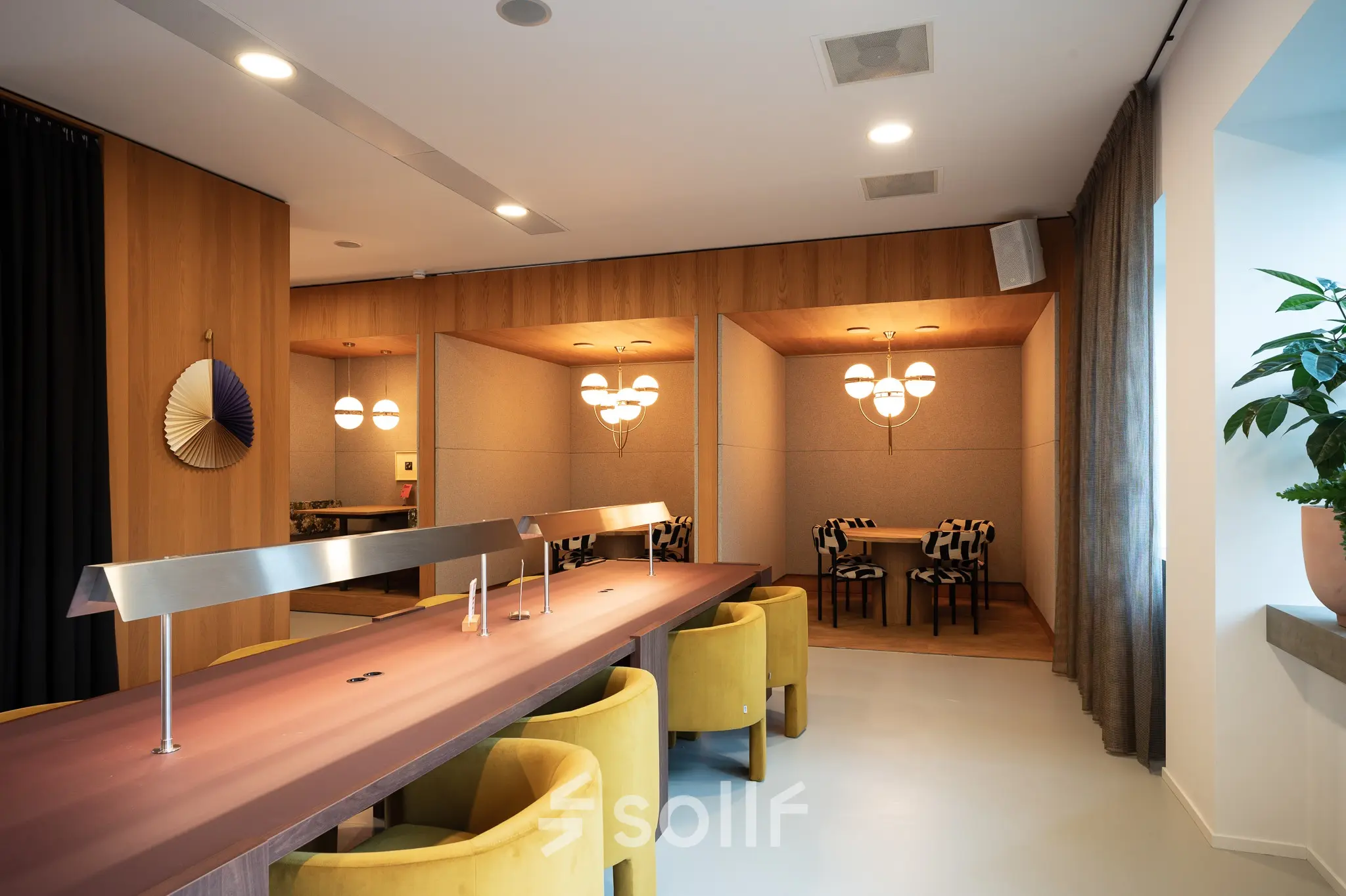 Moderne kantoorruimte met houten tafel en gele stoelen op Barbara Strozzilaan 101, Amsterdam Zuidas, geschikt voor werk of vergaderingen. Verfijnd interieur met decoratieve elementen en sfeerverlichting.