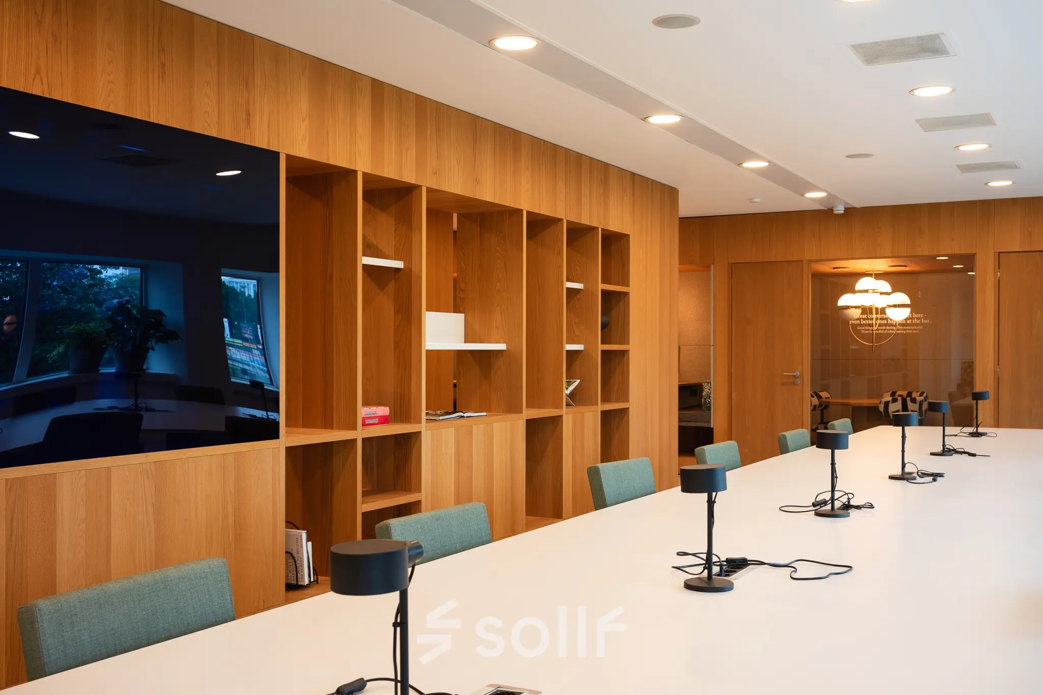 Moderne kantoorruimte met lange witte tafel, stoelen en ingebouwde kasten, ideaal voor vergaderingen of samenwerking. Perfect voor bedrijven die kantoorruimte willen huren in Amsterdam Zuidas.
