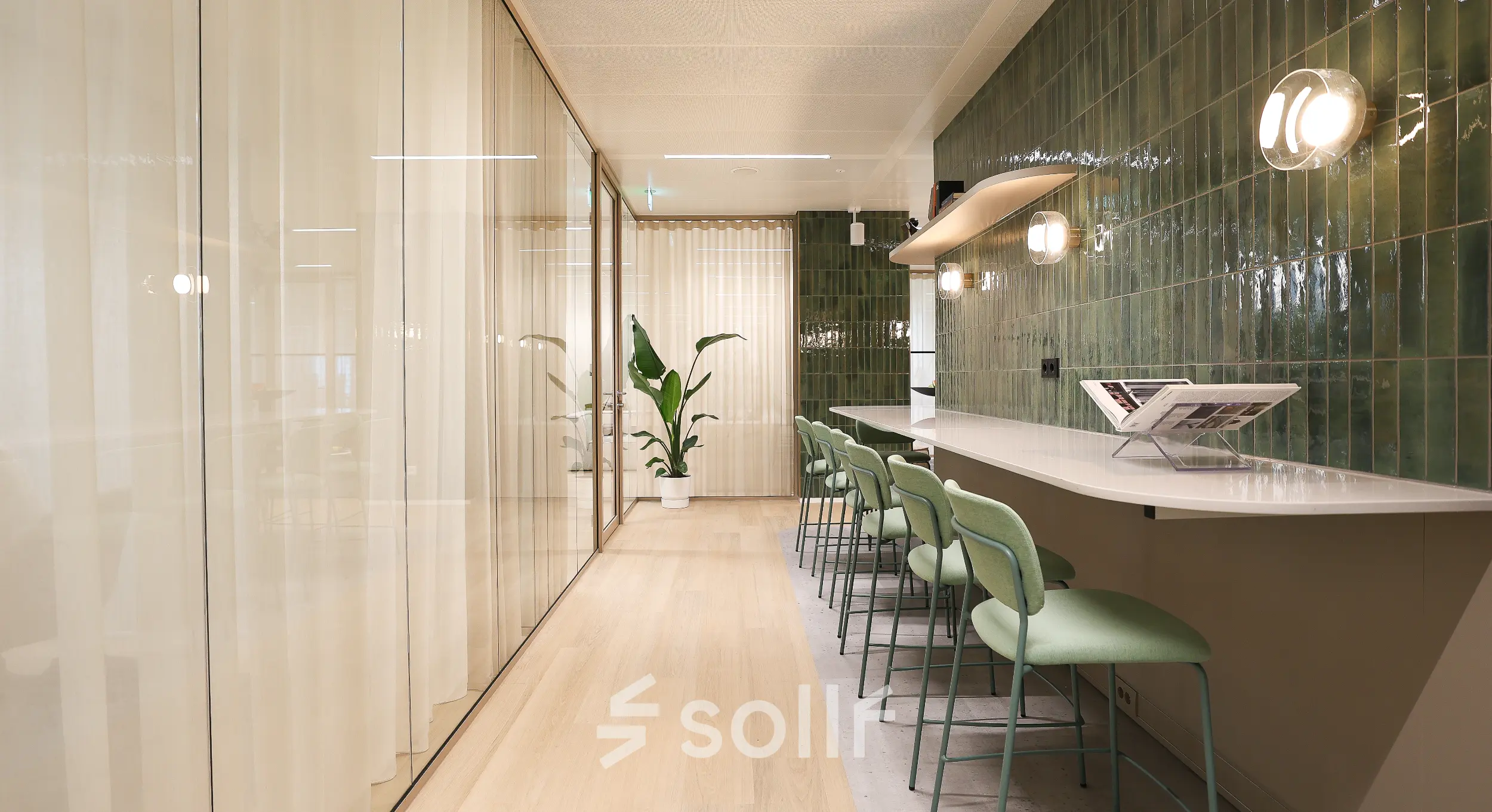 Moderne kantoorruimte te huur aan de Beethovenstraat 503 in Amsterdam Zuidas met groene tegels, hoge stoelen en glazen wanden voor een stijlvolle werkomgeving.