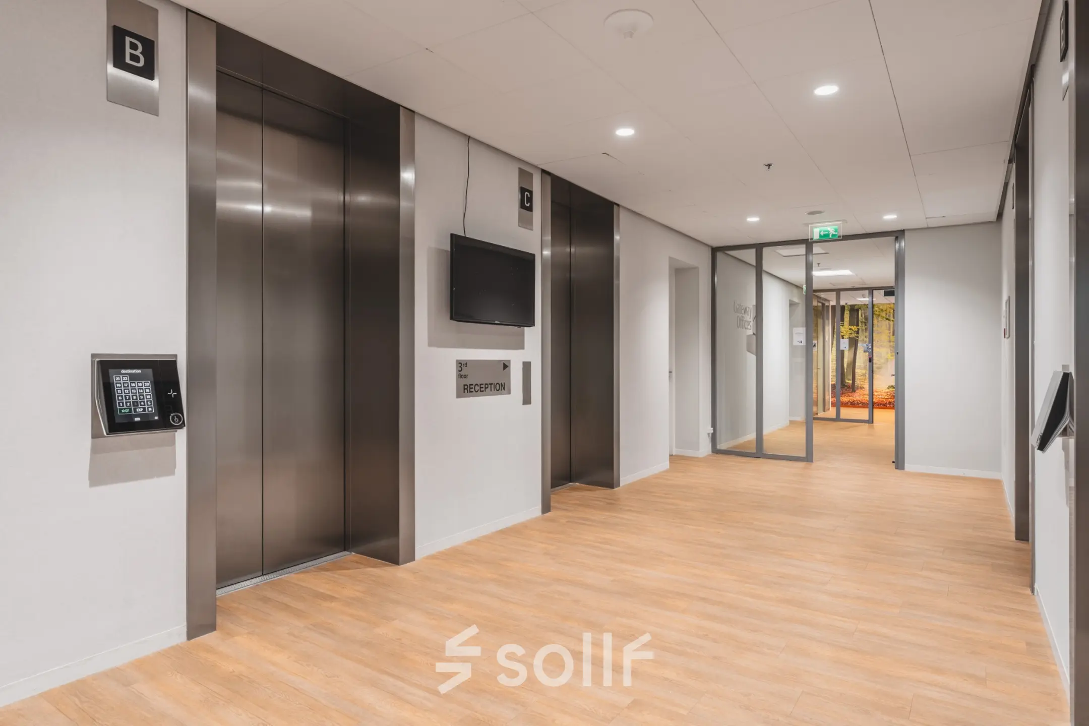 Moderne ontvangsthal op Claude Debussylaan 10 in Amsterdam Zuidas, met twee liften en een tv aan de muur. Perfecte locatie voor kantoorruimte huren met toegang tot diverse kantoren.