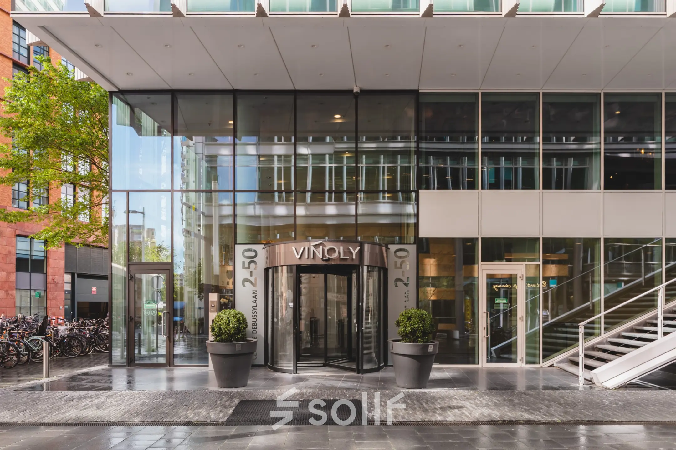 Voorzijde van kantoorpand op Claude Debussylaan 10 in Amsterdam Zuidas, met moderne glazen gevel. Geschikt voor kantoorruimte huren.