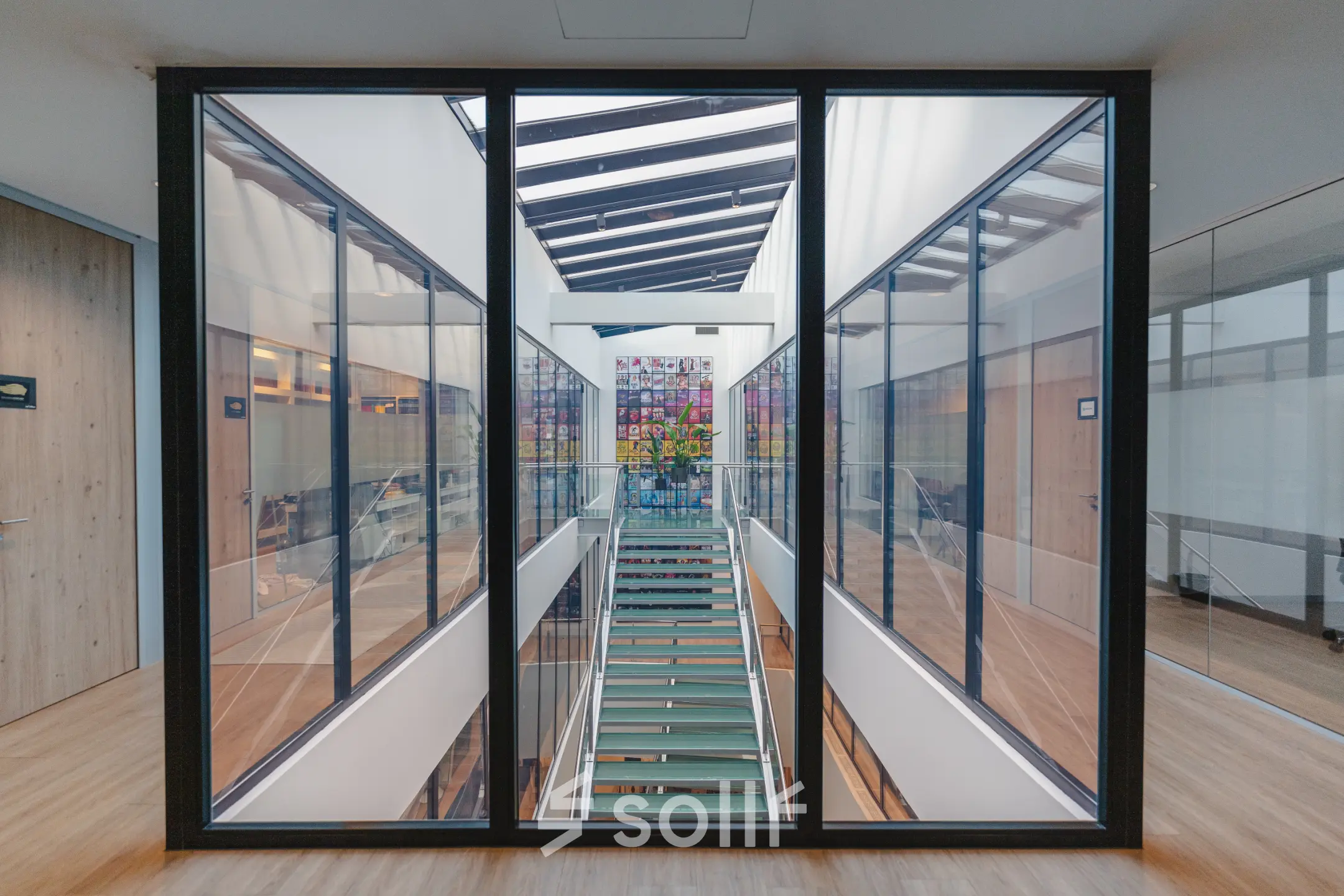 Overzicht van een modern kantoorpand op De Boelelaan 30 in Amsterdam Zuidas, met een glazen wand en een kleurrijk kunstwerk op de achtergrond.