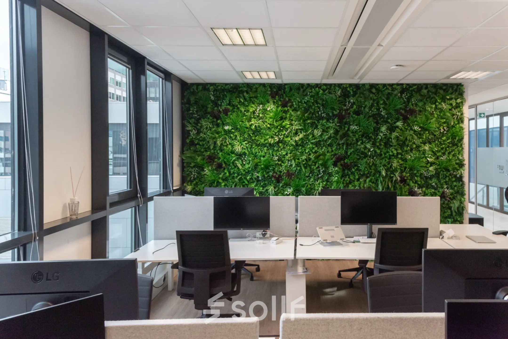 Gemeubileerd kantoor aan De Boelelaan 30 in Amsterdam Zuidas met groene wand, meerdere bureaus en computers, in een lichte werkruimte voor kantoorruimte huren.