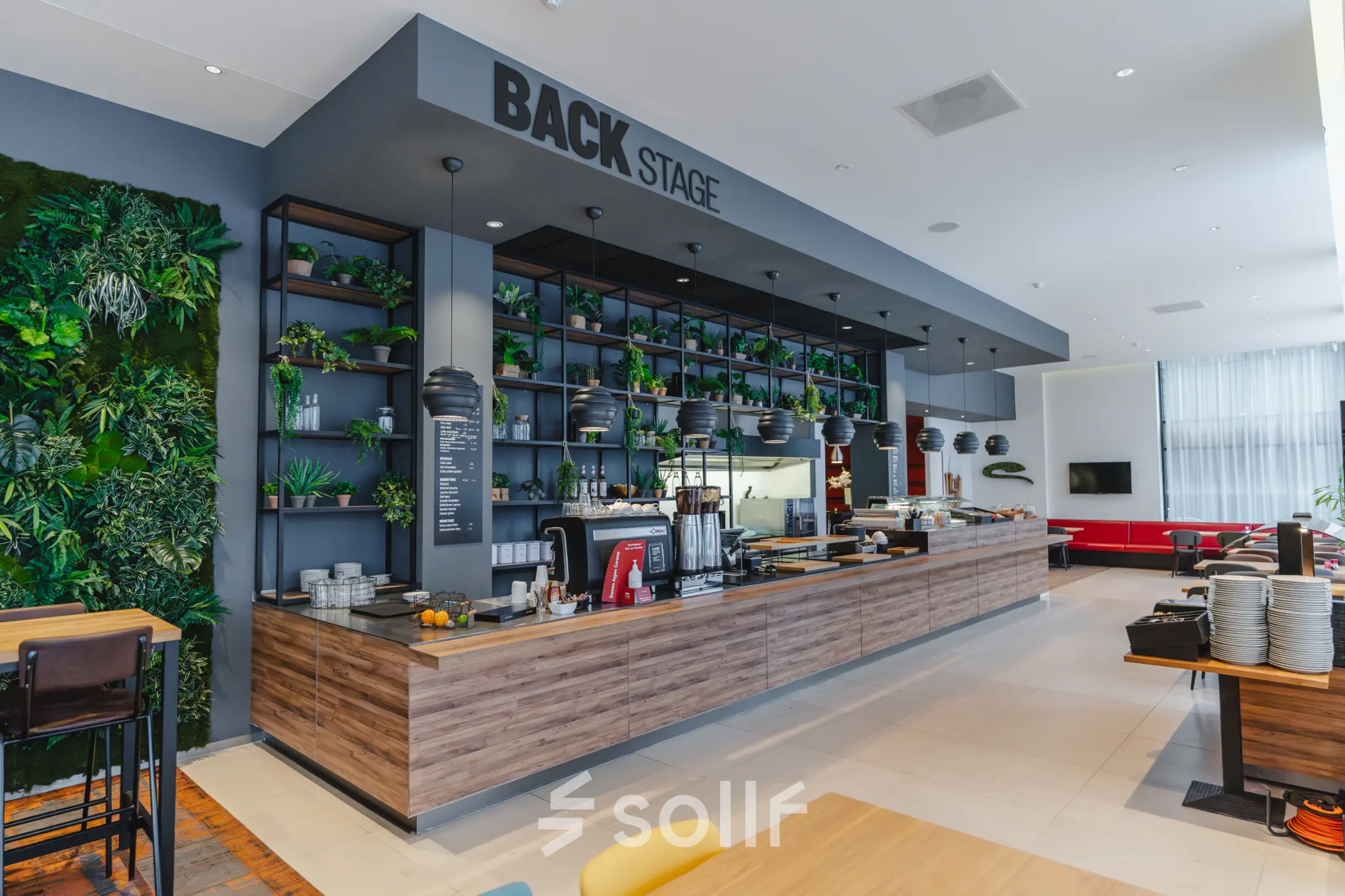 Moderne kantoorruimte huren met een ingerichte lounge op de Amsterdam Zuidas, De Boelelaan 30, met een lange houten bar en groene wanddecoraties.