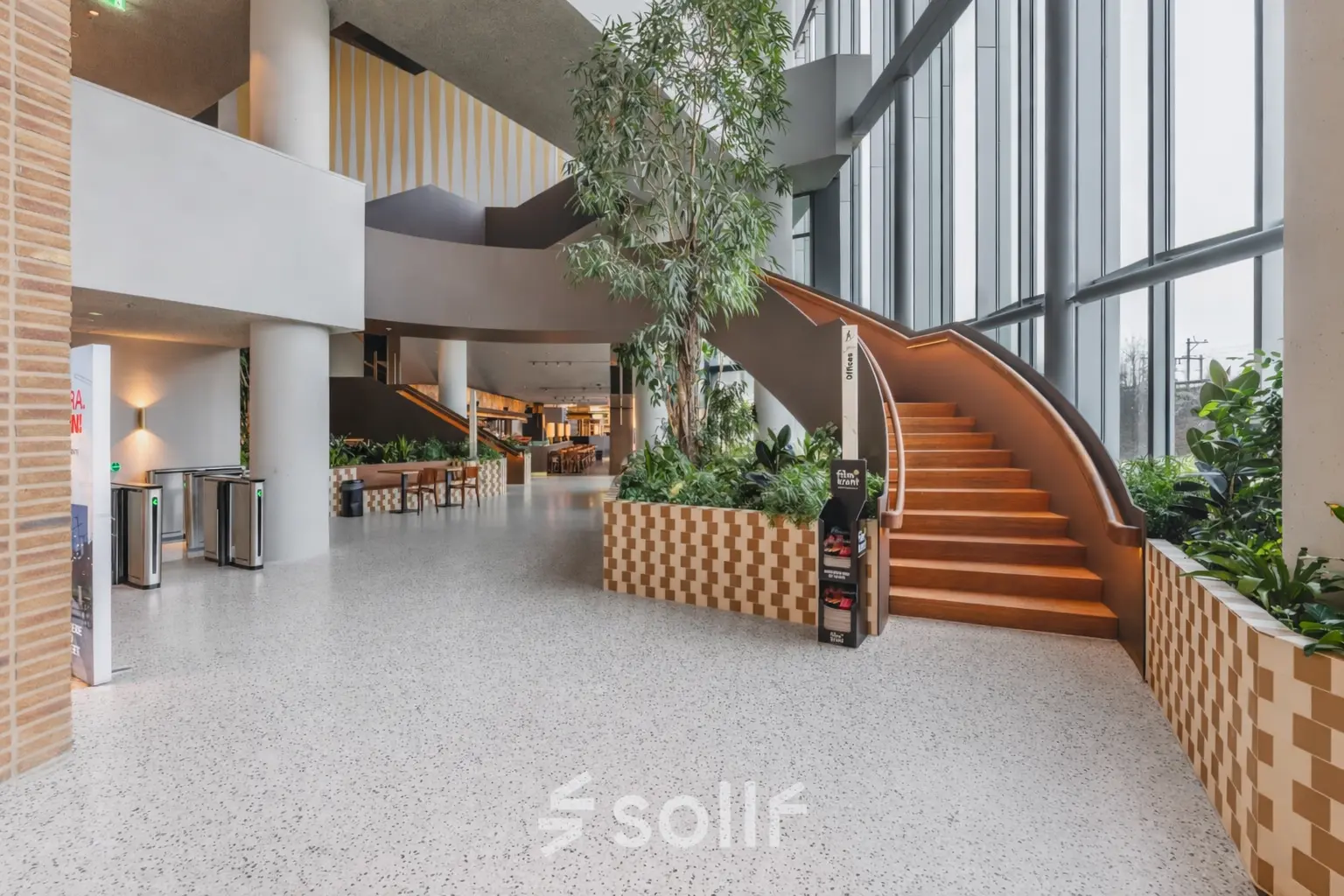 Entree van een modern kantoorpand aan de Hildegard Von Bingenstraat 44 in Amsterdam Zuidas met open trap en veel groen, ideaal voor kantoorruimte huren.