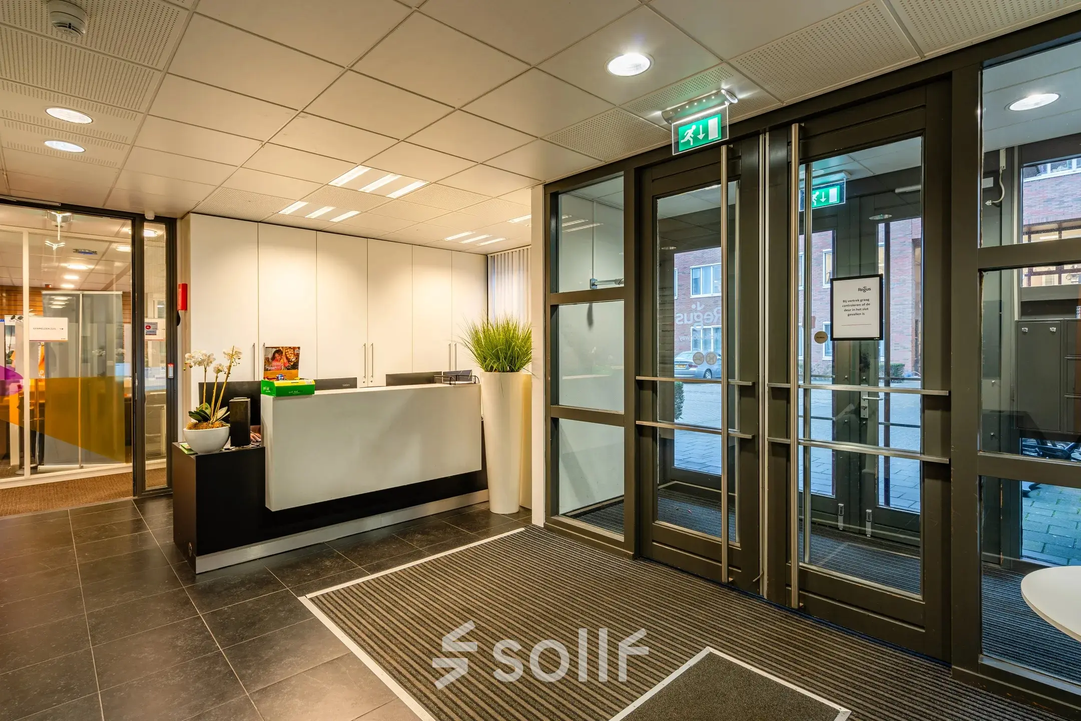 Kantoorpand op Het Rietveld 55-59, Apeldoorn, met een moderne entree en receptieruimte. De glazen deuren bieden toegang tot de kantoorruimte. Ideaal voor wie een kantoor wil huren.