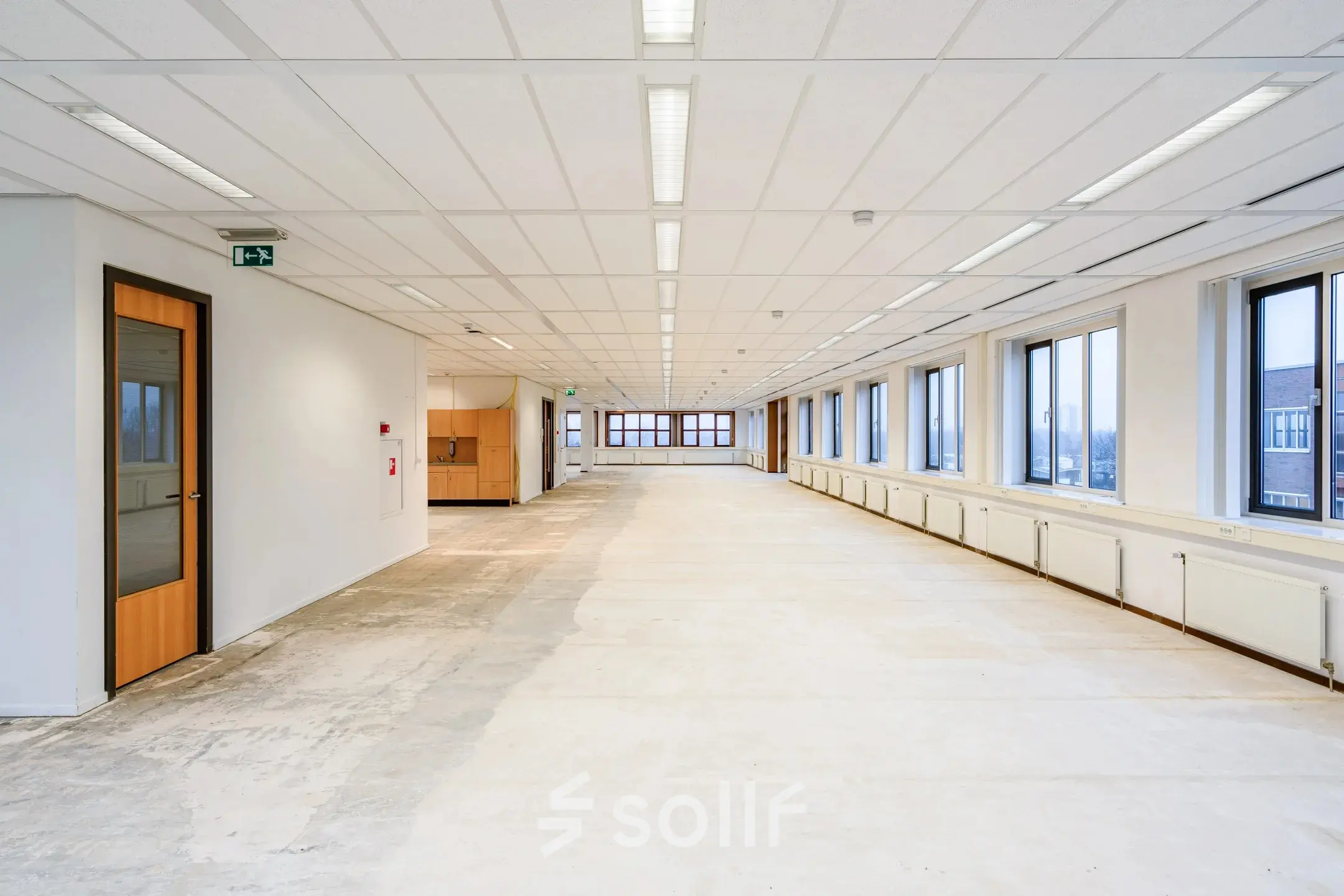 Grote, lichte kantoorruimte in kantoorpand aan Het Rietveld 55-59, Apeldoorn, zonder meubilair. Lange ruimte met ramen aan één zijde. Geschikt voor huur als open kantoor.