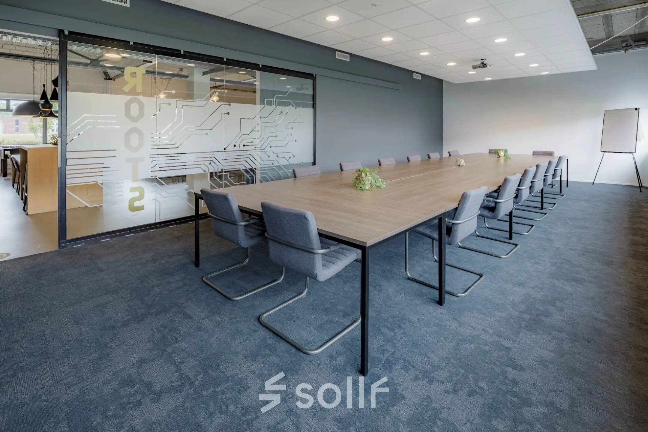 Kantoorruimte huren op Oude Apeldoornseweg 41-45 in Apeldoorn met een moderne vergaderruimte, lange tafel, comfortabele stoelen en glazen deur met opdruk. Ideaal kantoorpand voor vergaderingen.