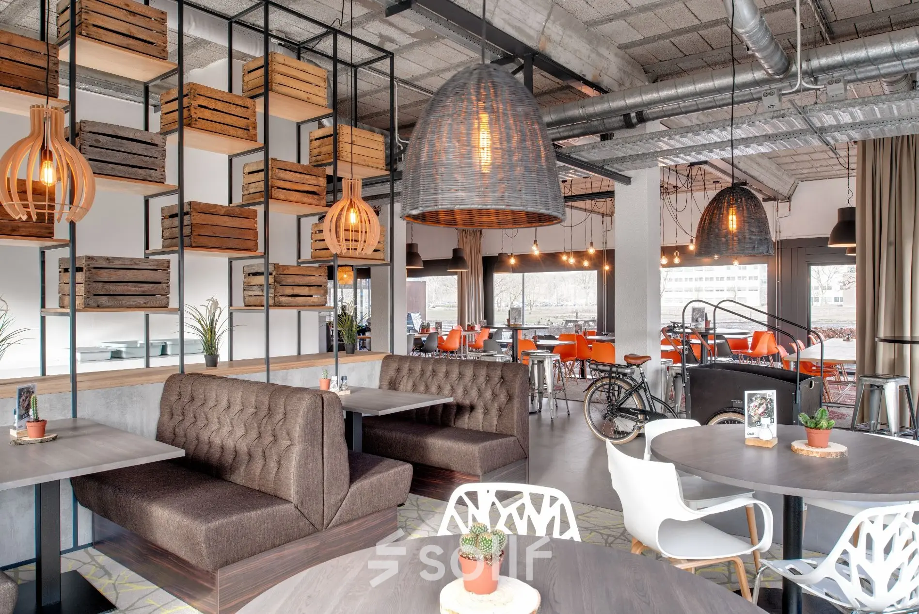 Moderne kantoorruimte huren aan Oude Apeldoornseweg 41-45, Apeldoorn. Ruim interieur met gezellige zithoeken, houten accenten en hanglampen. Ideaal voor ontspannen werkoverleg en creatieve brainstormsessies.
