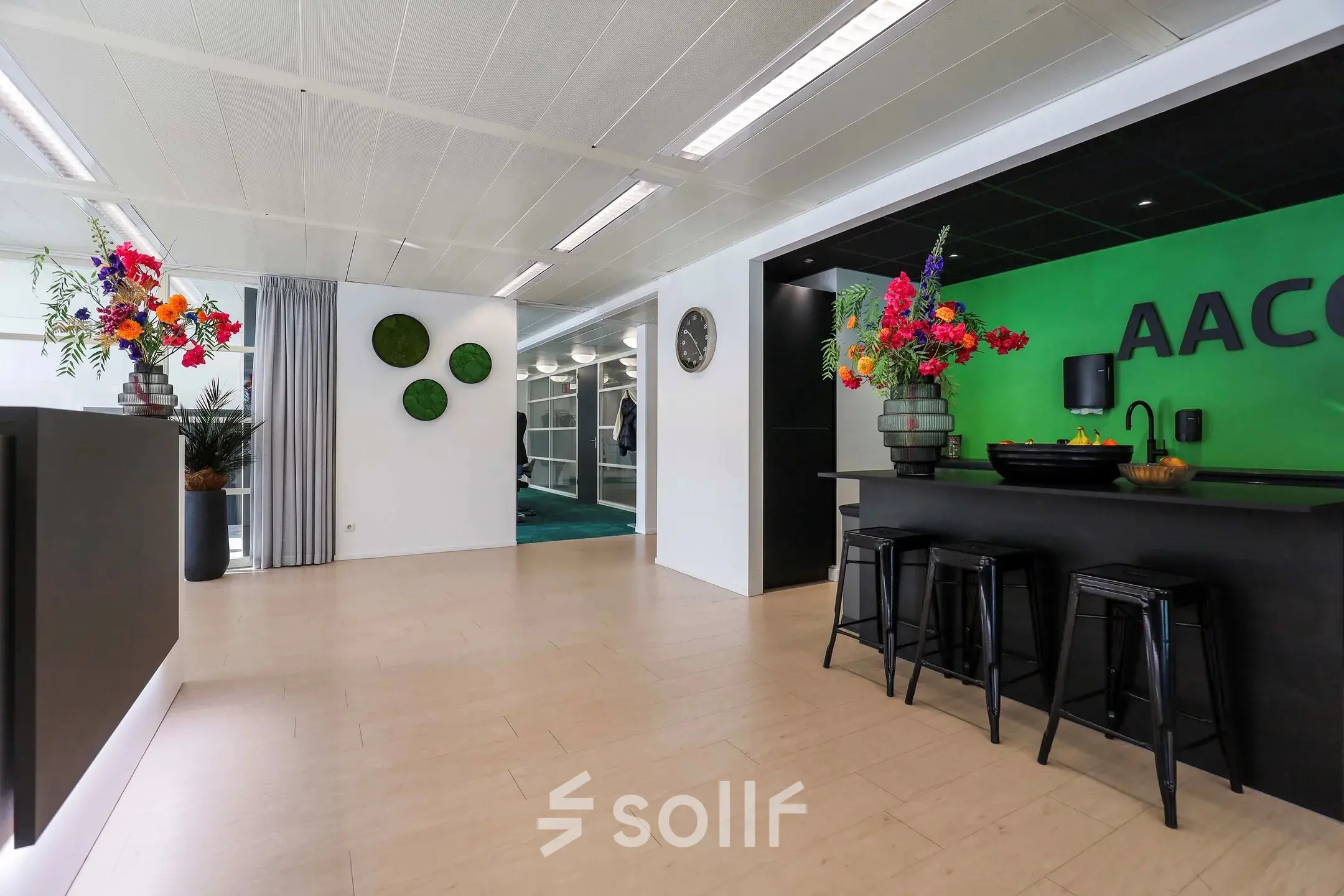 Kantoorruimte in Apeldoorn op Prins Willem-Alexanderlaan 301 met moderne inrichting, inclusief kleurrijke bloemen, enkele krukken en een open vloerplan voor kantoor activiteiten. Ideaal voor huren.