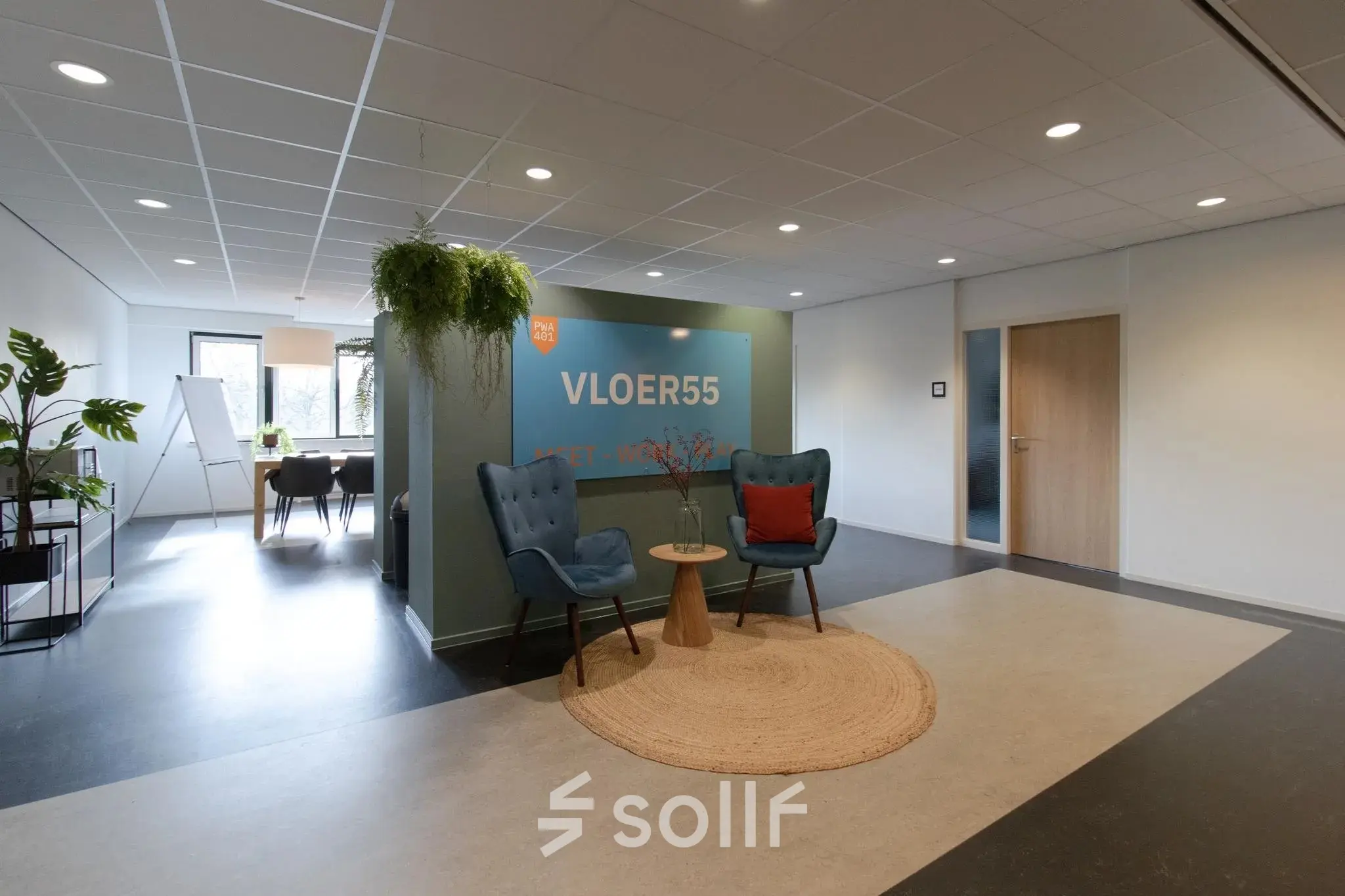 Kantoorinterieur met een zitruimte en een vergadertafel op de achtergrond, geschikt voor kantoorruimte huren in Apeldoorn.