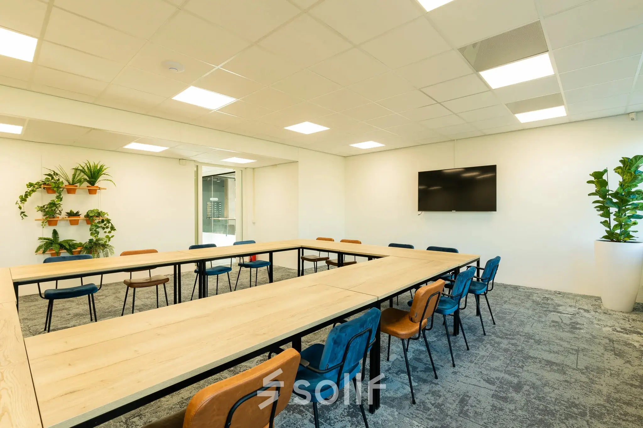 Kantoorruimte in Apeldoorn aan de Prins Willem Alexanderlaan 701 met een moderne inrichting, bestaande uit een grote tafel, stoelen en planten. Beschikbaar voor gebruik als vergaderruimte.