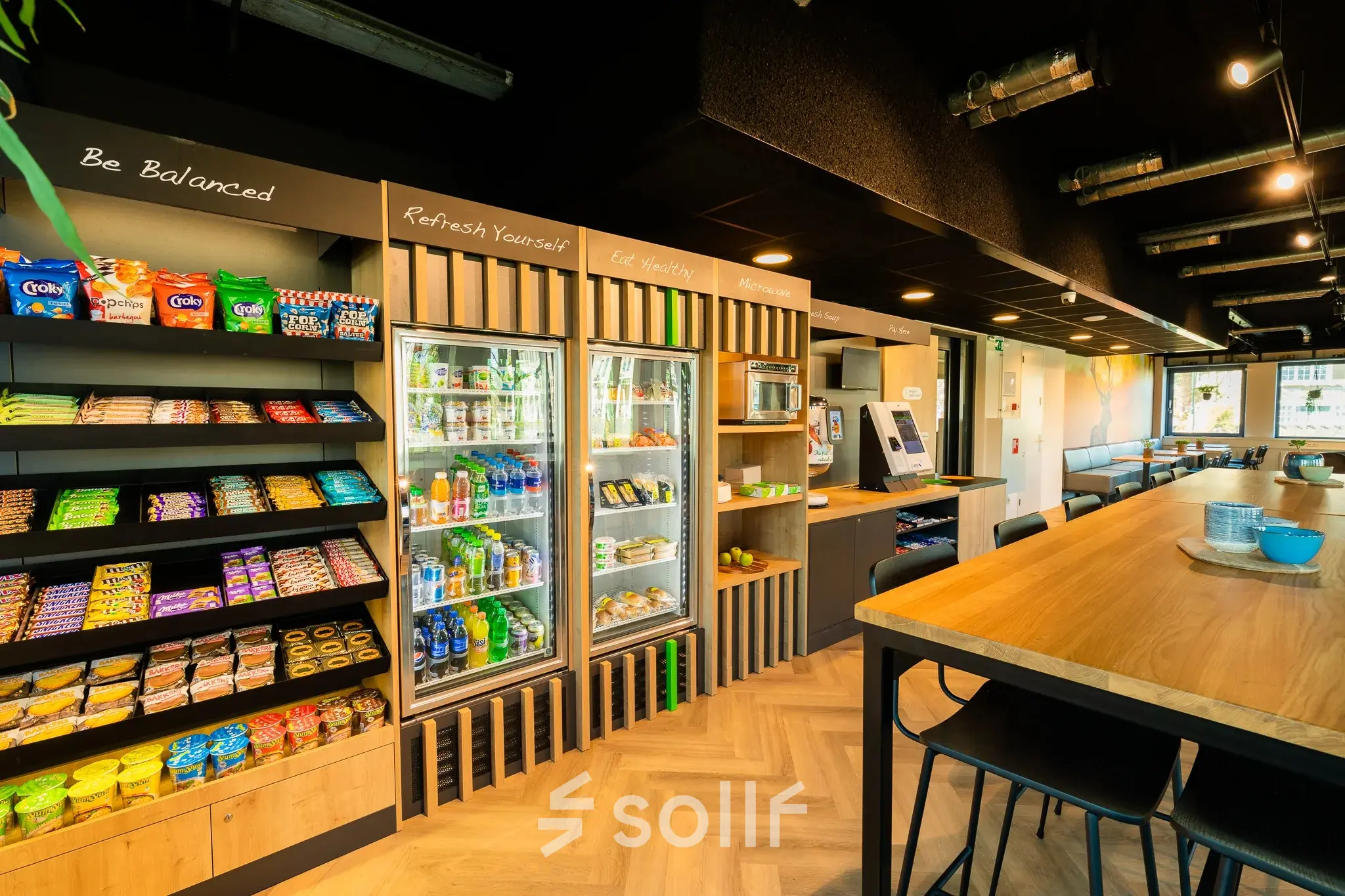 Moderne pantry met houten vloer, gevulde snackrekken en drankjeskoelkast, ideaal voor kantoorruimte huren op Prins Willem Alexanderlaan 701, Apeldoorn.