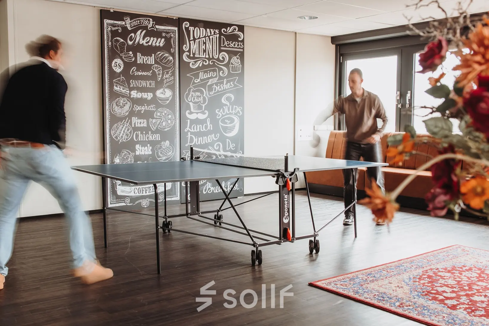 Moderne kantoorruimte met tafeltennistafel in Arnhem IJsseloord. Twee mensen spelen tafeltennis, ideaal voor ontspanning tijdens werktijd. Unieke kans om kantoorruimte te huren in dit kantoorpand op Vlamoven 34.