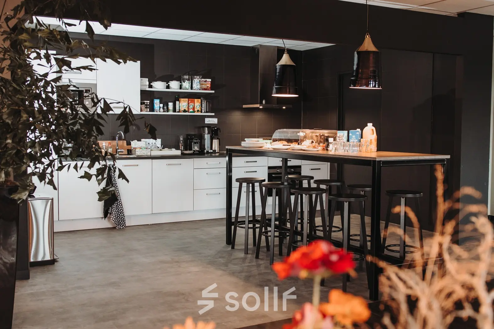 Moderne pantry in een kantoorpand op Vlamoven 34, Arnhem IJsseloord. Ruimte met strak design, voorzien van een hoog tafelblad en krukken, ideaal voor kantoorruimte huren.