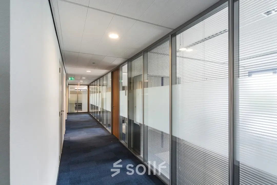 Kantoorpand Arnhem Zuid bij Kronenburgsingel 525 met een moderne gang met glazen wanden en tapijtvloer, geschikt voor kantoorruimte huren.