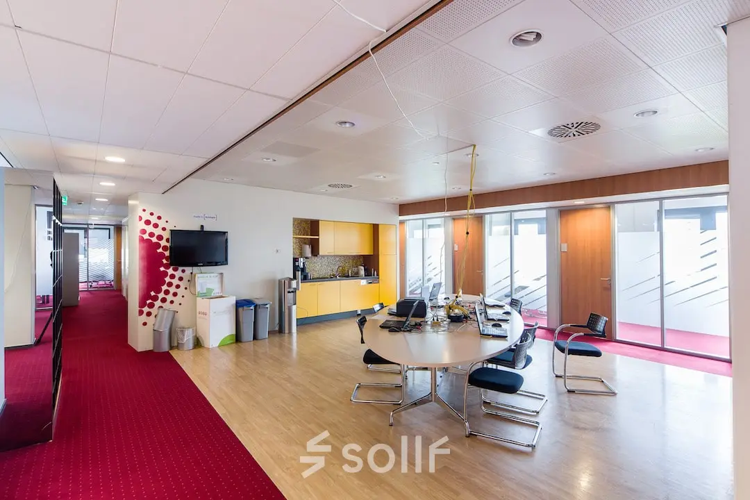 Kantoorruimte huren in Arnhem Zuid met moderne vergadertafel, stoelen, tv-scherm en koffiehoek op Kronenburgsingel 525.