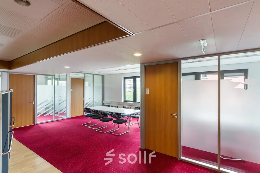 Kantoorruimte huren in Arnhem Zuid: moderne werkruimte met rode vloerbedekking, glazen wanden en vergaderruimte gelegen op Kronenburgsingel 525. Deze kantoorruimte biedt een professionele omgeving voor zakelijke activiteiten.