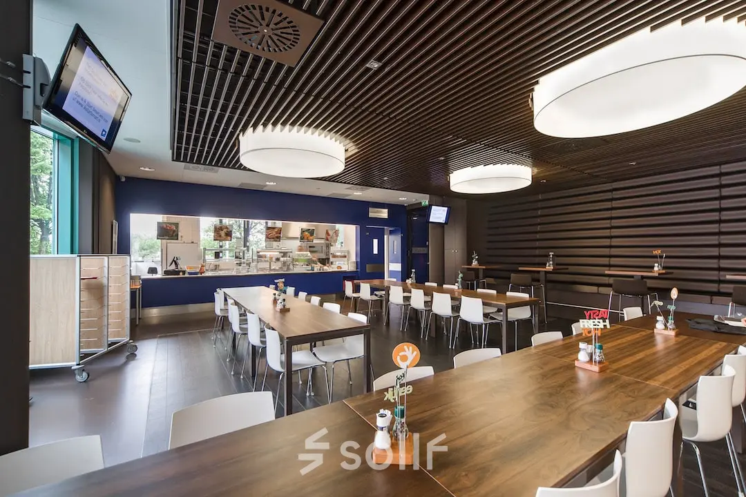 Binnenruimte in het kantoorpand op Kronenburgsingel 525, Arnhem Zuid met moderne tafels en een bedrijfskeuken. Ideaal voor kantoren die ruimte willen huren in een functionele omgeving.