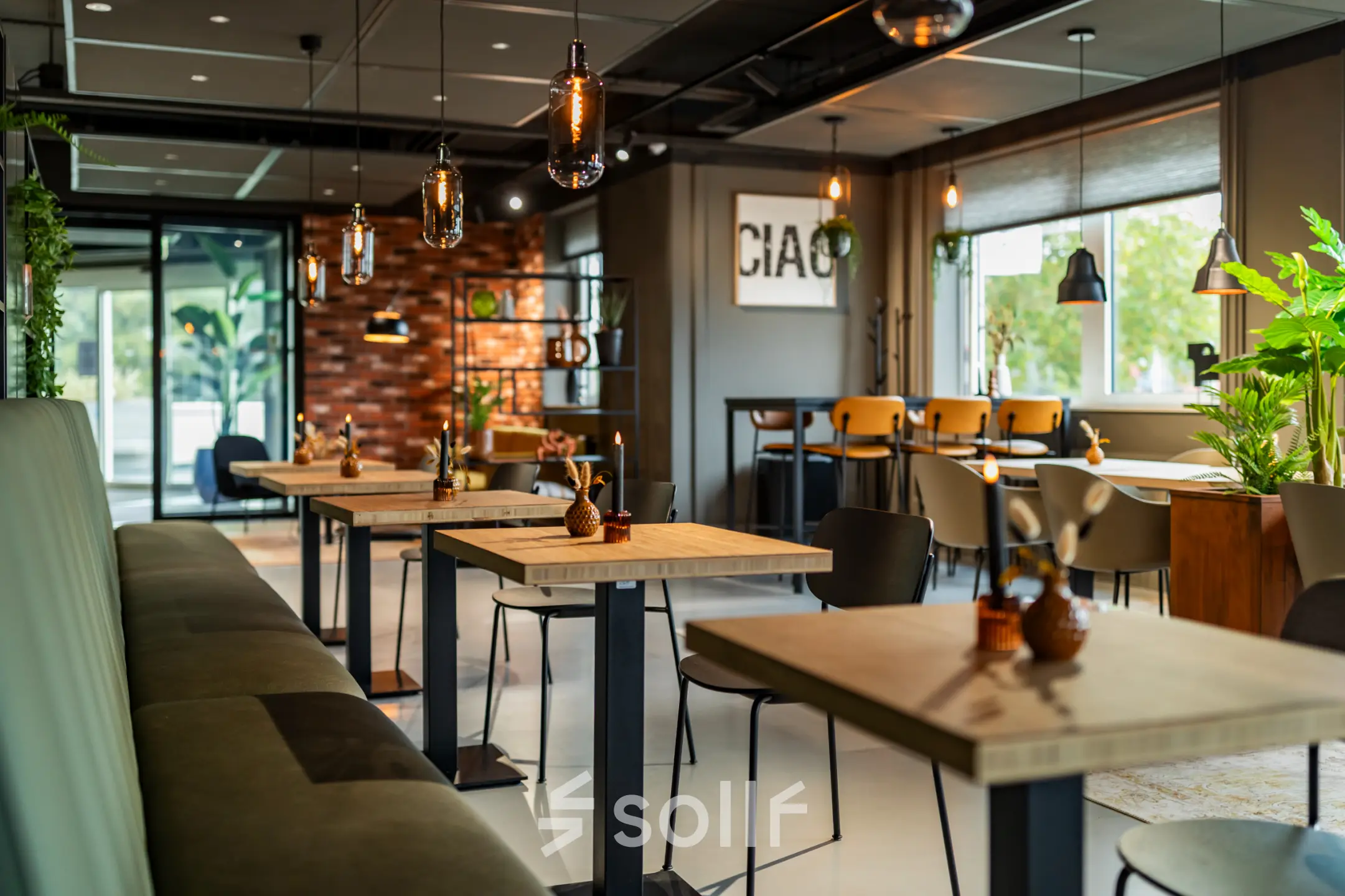 Moderne, sfeervol ingerichte kantoorruimte met houten tafels, comfortabele stoelen en hangende lampen in een lichte omgeving om te huren in Barneveld.