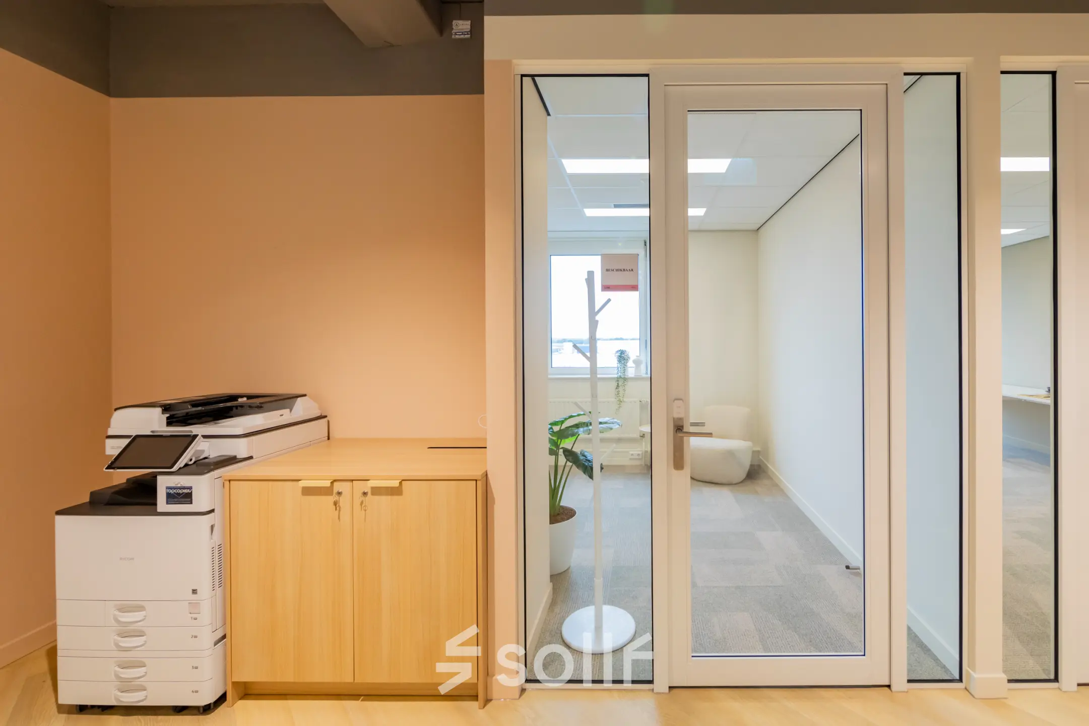 Kantoorruimte huren in Barneveld aan Baron van Nagellstraat 136, met een moderne kantoorpand-interieur, een printer en een glazen deur die naar een lichte werkplek leidt.