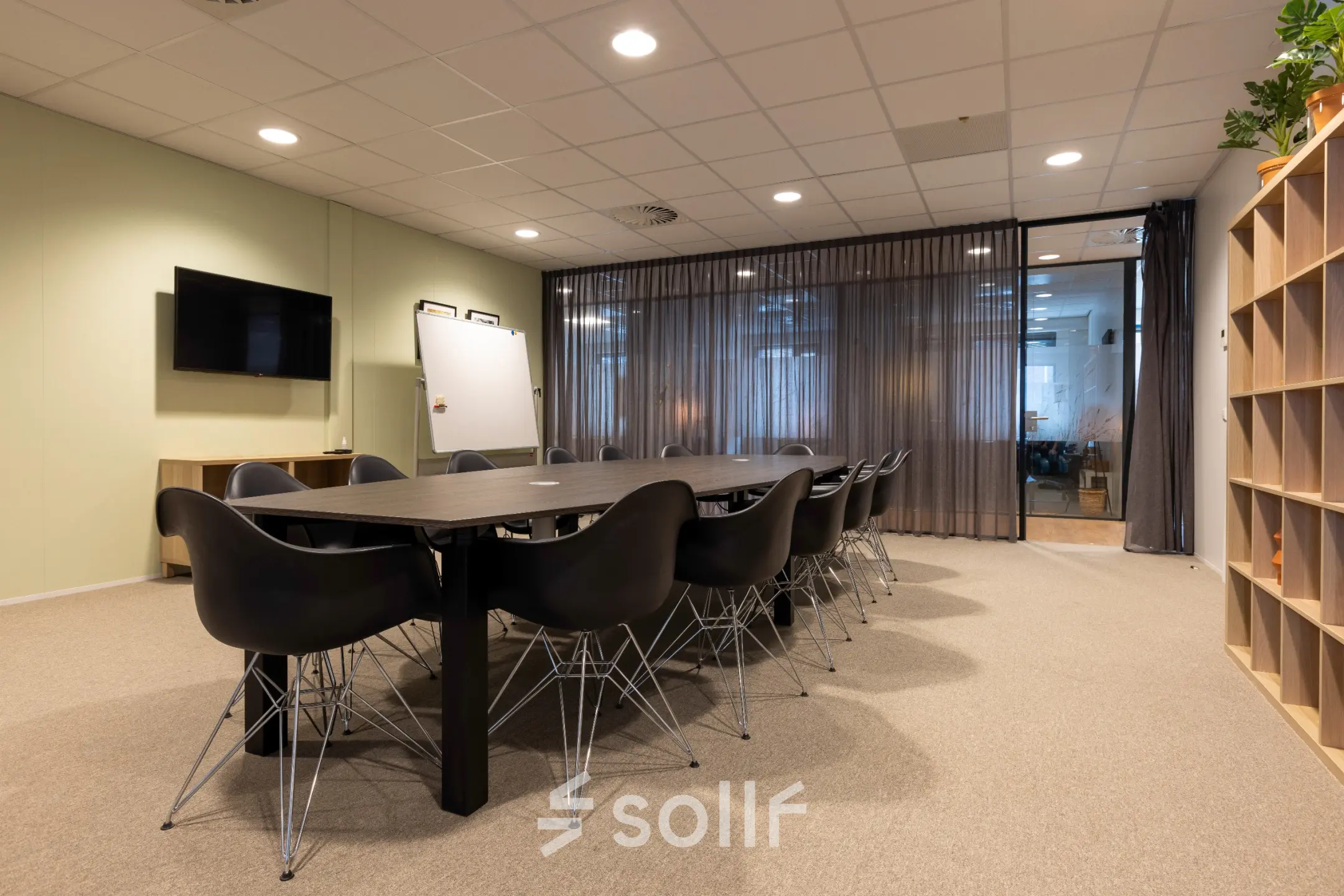 Moderne conferentieruimte met een lange zwarte tafel en stoelen, tegen een achtergrond van glazen wanden in een kantoorpand voor huur in Bodegraven.