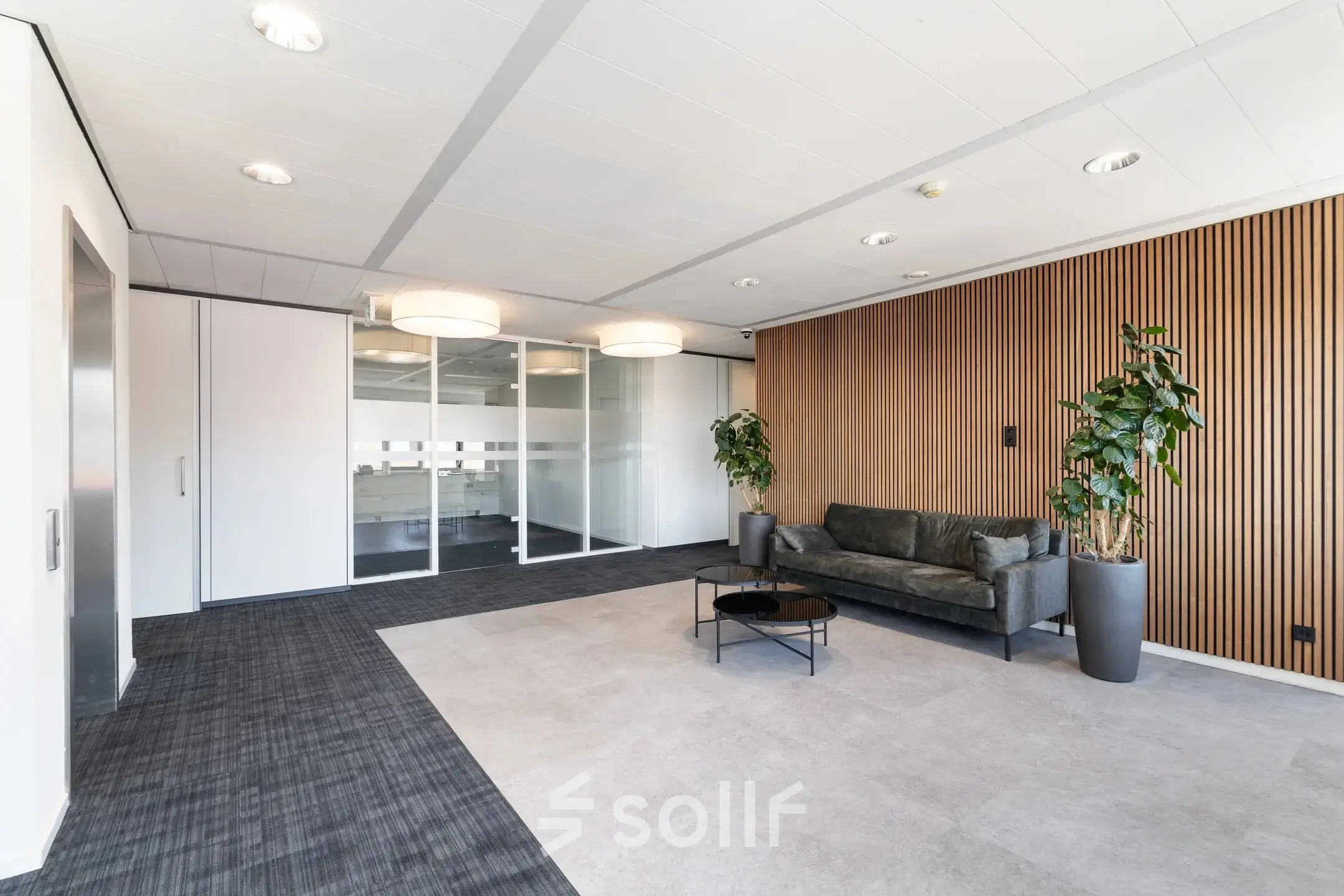 Moderne kantoorruimte op Tolnasingel 1 - 3 in Bodegraven, met glazen wanden, houten wandbekleding en een stijlvolle bank. Ideaal voor wie een kantoorpand wil huren.