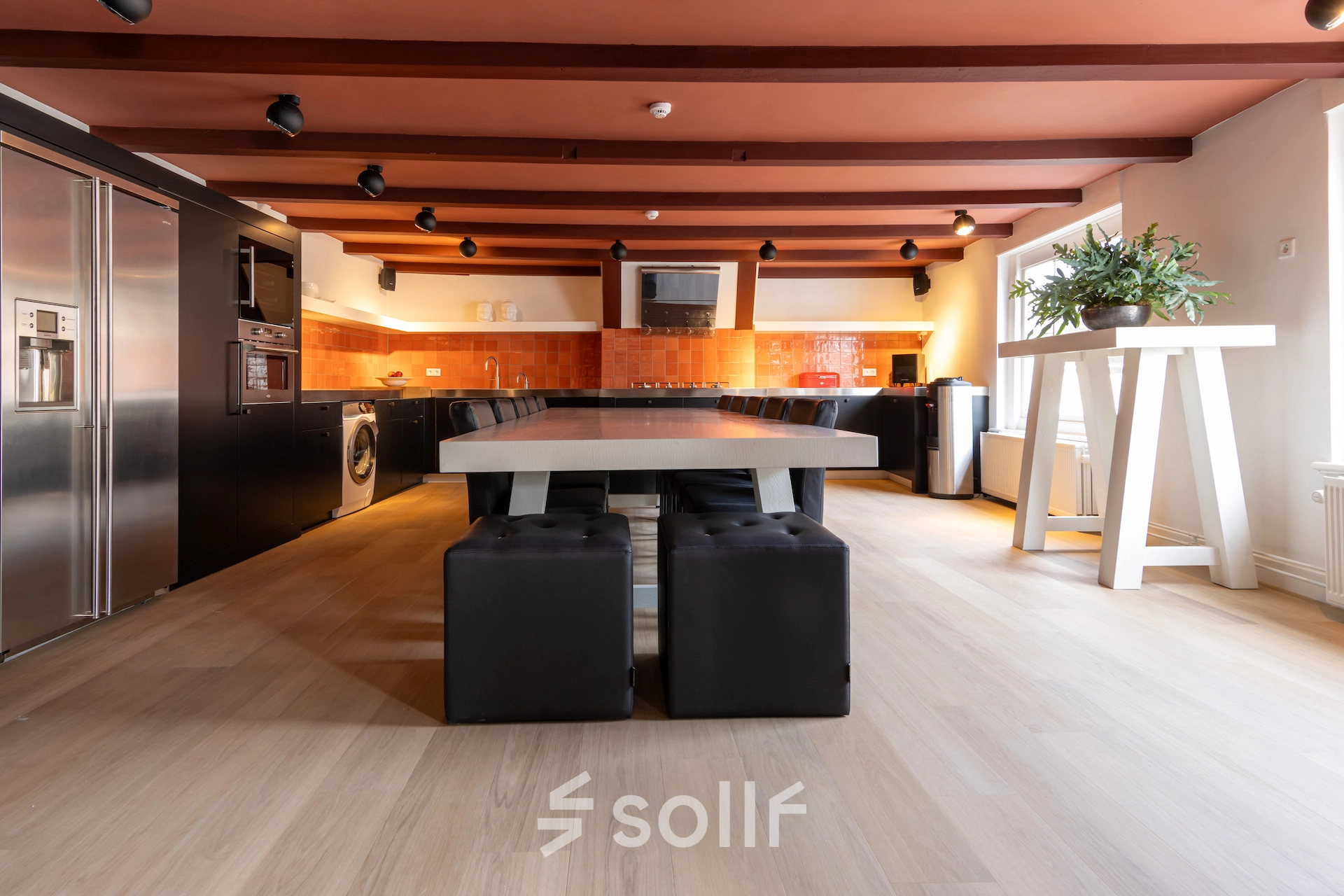 Moderne kantoorruimte huren in Breda met grote houten tafel, comfortabele zitplaatsen en goed uitgeruste keuken in industriële stijl gelegen aan Catharinastraat 16, Breda Centrum-Station.