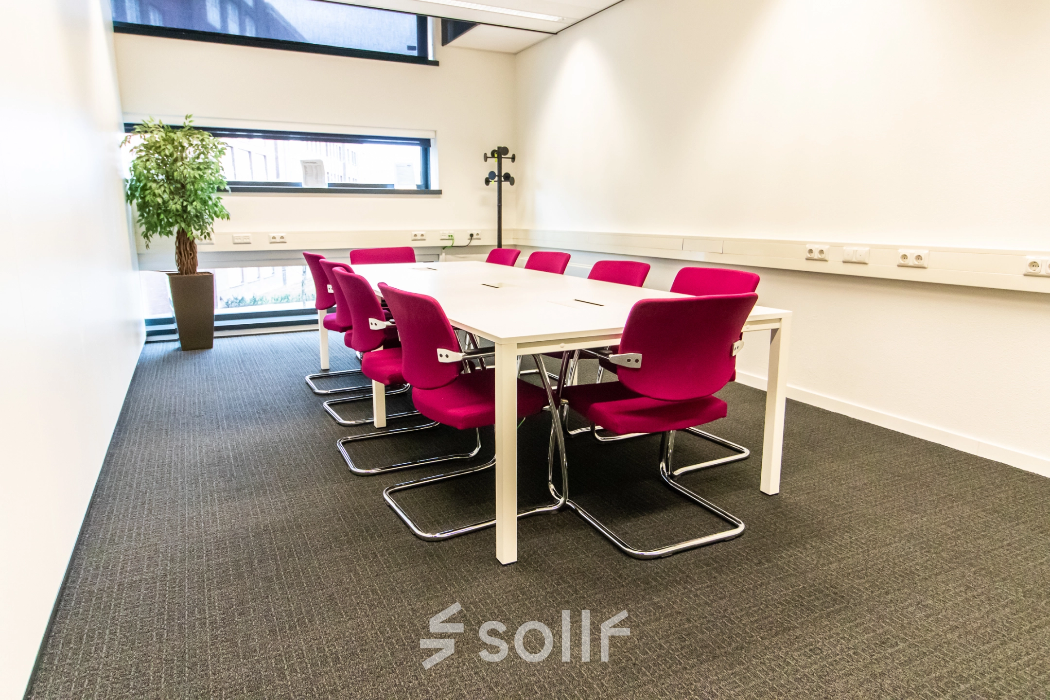 Vergaderruimte met roze stoelen rond een tafel in een kantoor op Ceresstraat 1, Breda Centrum-Station, geschikt voor kantoorruimte huren.