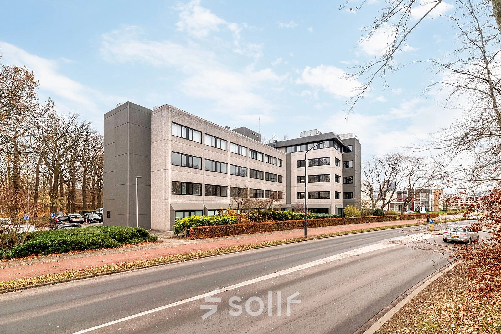 Kantoorpand aan de Heerbaan 14 in Breda Oost-Brabantpark met meerdere verdiepingen, omgeven door bomen, langs een weg. Perfecte locatie voor kantoorruimte huren.