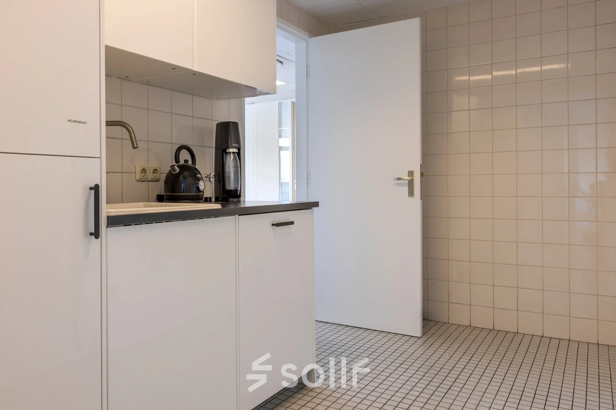 Kantoorruimte te huur aan de Druivenstraat 25-31 in Breda Oost, met een compacte kitchenette voorzien van een koffiezetapparaat en tegelwanden, ideaal voor kantoorgebruik.