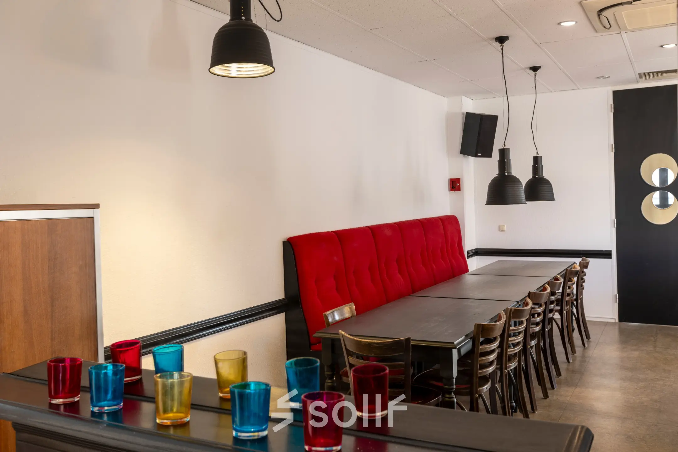 Herkenbare kantoorpand ambiance in Breda Oost aan Druivenstraat 25-31 met een strak ingerichte ruimte voorzien van een lange tafel en kleurrijke glazen op een kast.