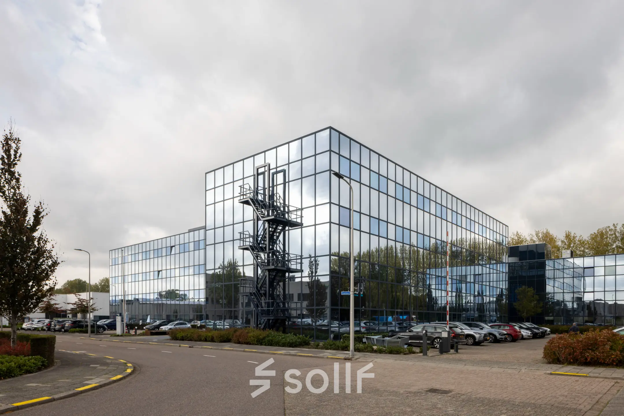 Modern kantoorpand met spiegelende gevel aan de Essebaan 63 in Capelle aan den IJssel, met parkeergelegenheid op de voorgrond.