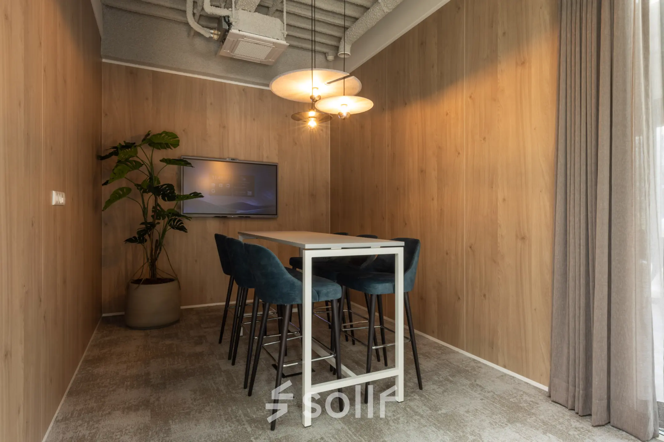 Moderne kantoorruimte te huur met hoge tafel, blauwe stoelen en scherm aan de muur in Capelle aan den IJssel.
