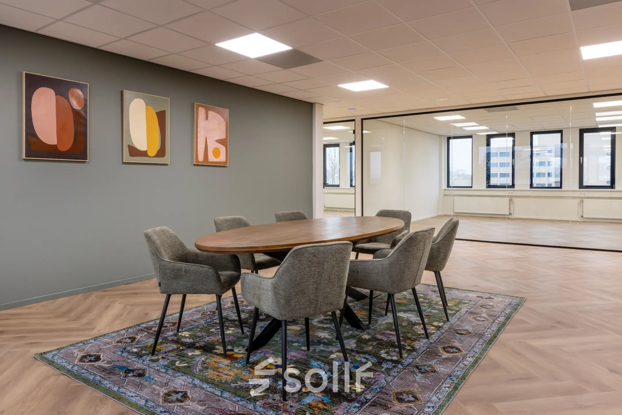 Moderne kantoorruimte met houten vergadertafel en zes stoelen op een kleurrijk tapijt, gelegen aan Vlierbaan 20, Capelle aan den IJssel. Ideale plek om kantoorruimte te huren voor zakelijke bijeenkomsten.