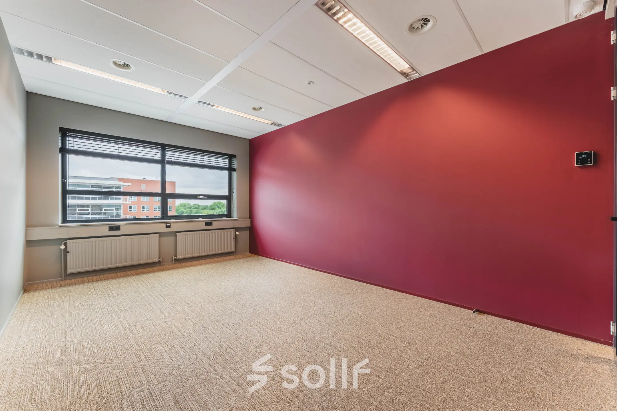 Kantoorruimte te huur in De Meern op Rijnzathe 12, met rood accentmuur en groot raam dat zorgt voor veel lichtinval. Perfecte ruimte om een eigen kantoor te creëren.