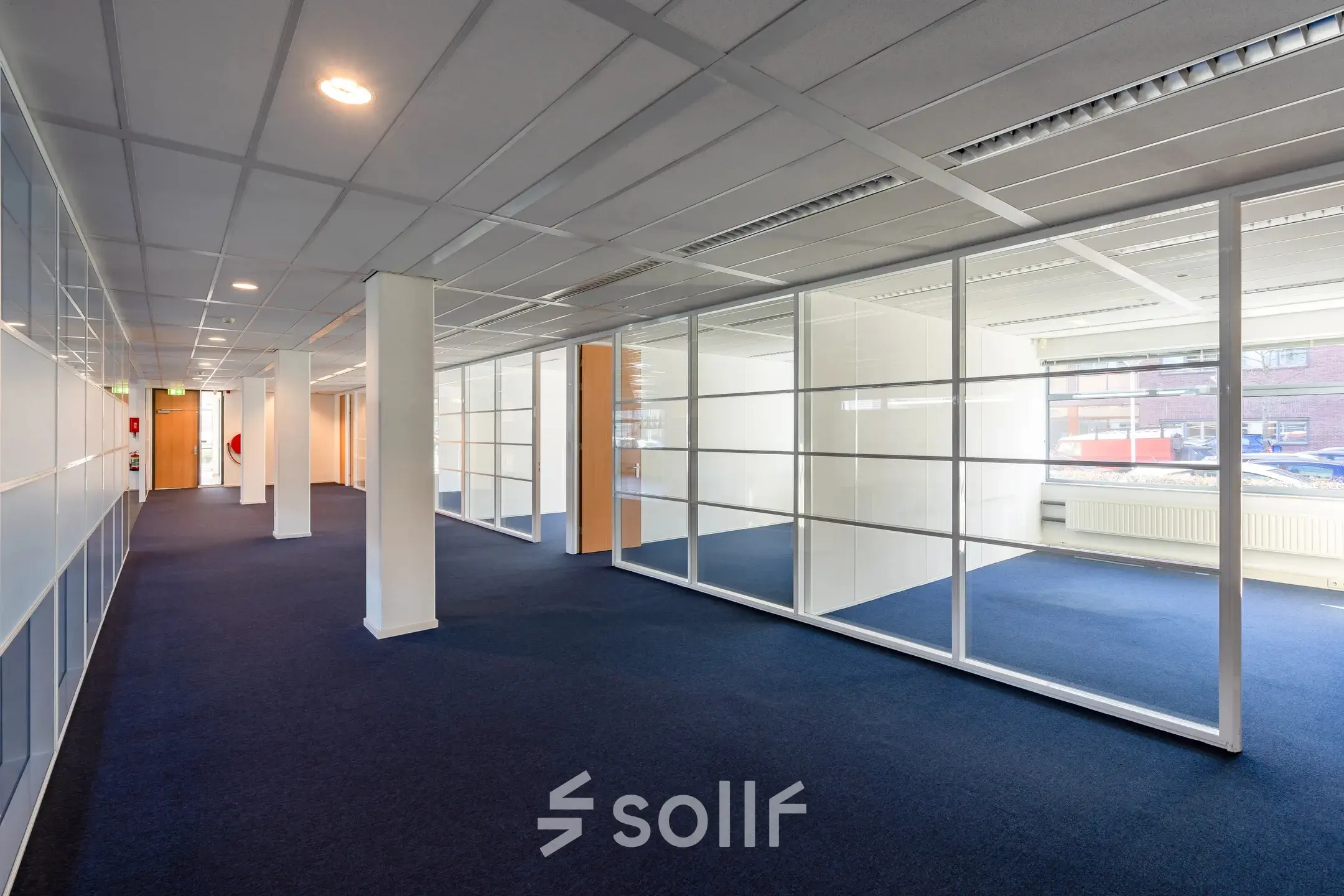 Binnenkant van een kantoorruimte op Delftechpark 17-19 in Delft met glazen wanden en blauw tapijt, ideaal voor werkruimtes of kantoren te huur.