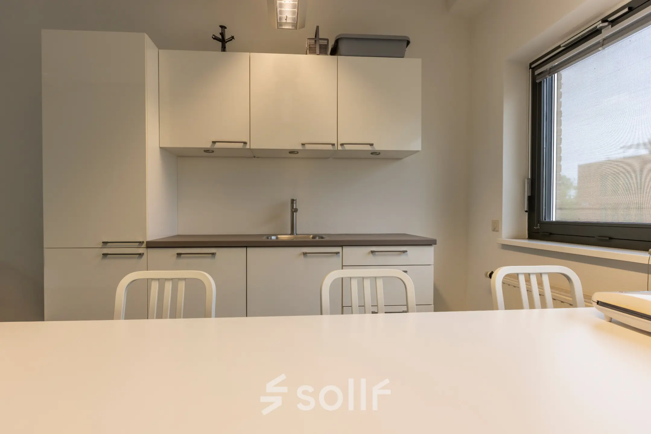 Moderne kantoorruimte in Delft met strakke keukenfaciliteiten en neutrale tinten, ideaal voor ontspanning of informele bijeenkomsten tijdens een drukke werkdag.