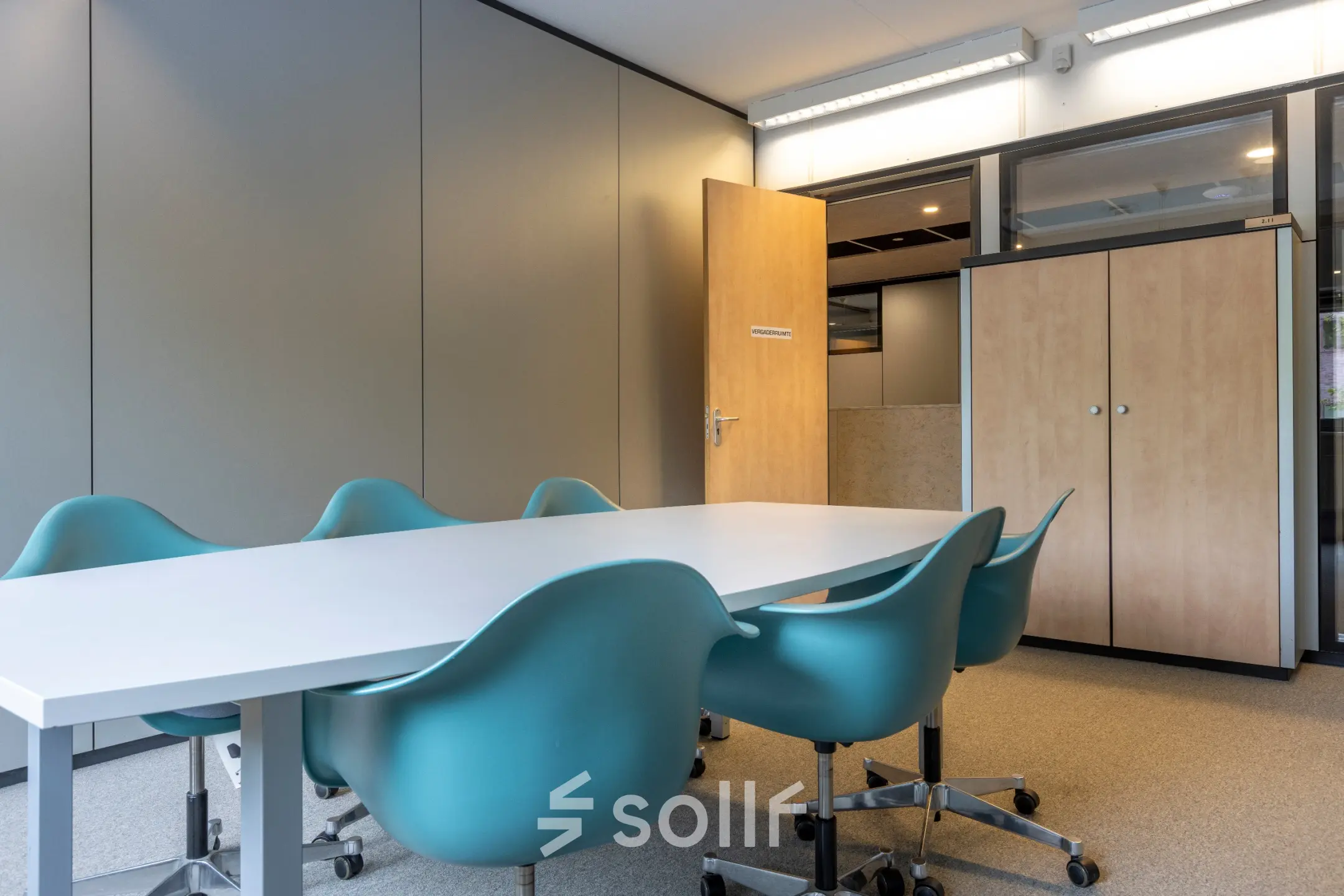 Vergaderruimte in kantoorpand op Delftechpark 9, Delft met lange tafel, blauwe stoelen en een kast. Perfect voor kantoorruimte huren die inspirerend en functioneel is.