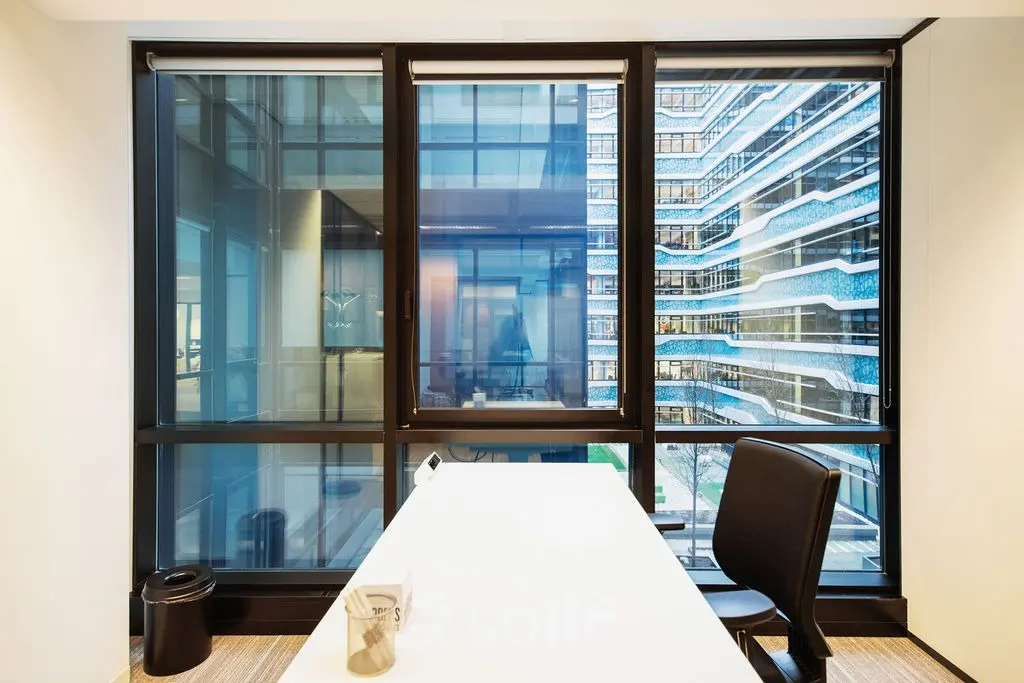 Kantoorruimte huren in Den Haag Centrum met een moderne werkplek voorzien van een groot raam met uitzicht op karakteristieke architectuur. De ruimte heeft een strakke inrichting met een tafel en stoel.