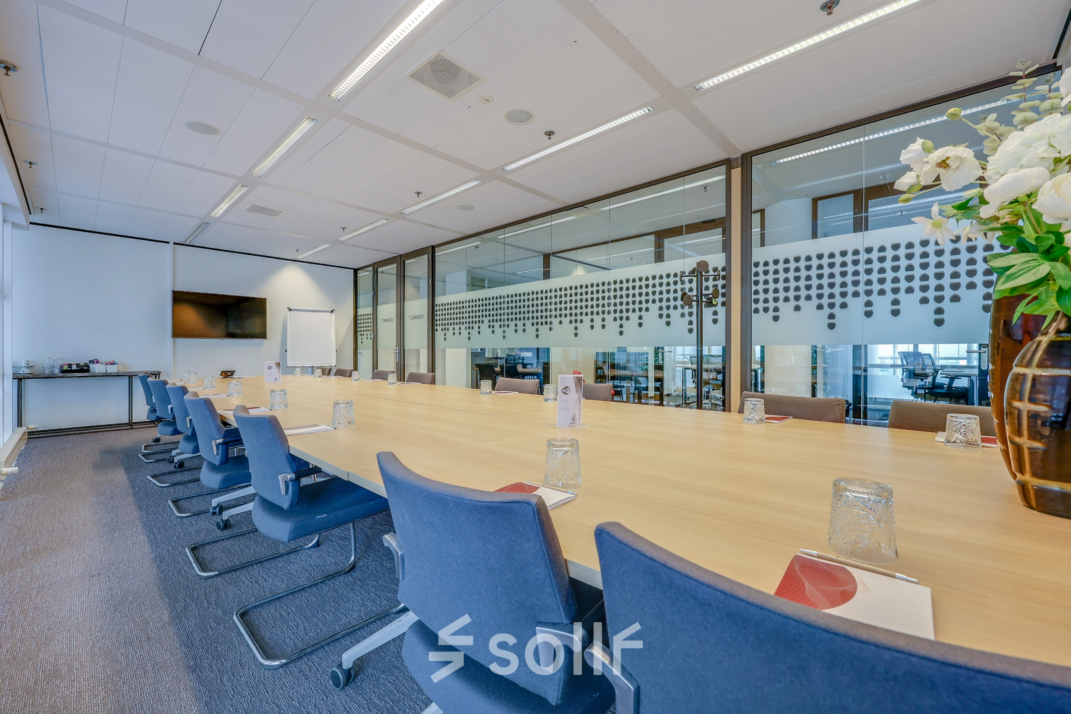 Vergaderruimte in kantoorpand op Kalvermarkt 53, Den Haag Centrum, met lange tafel, stoelen en glazen wand.