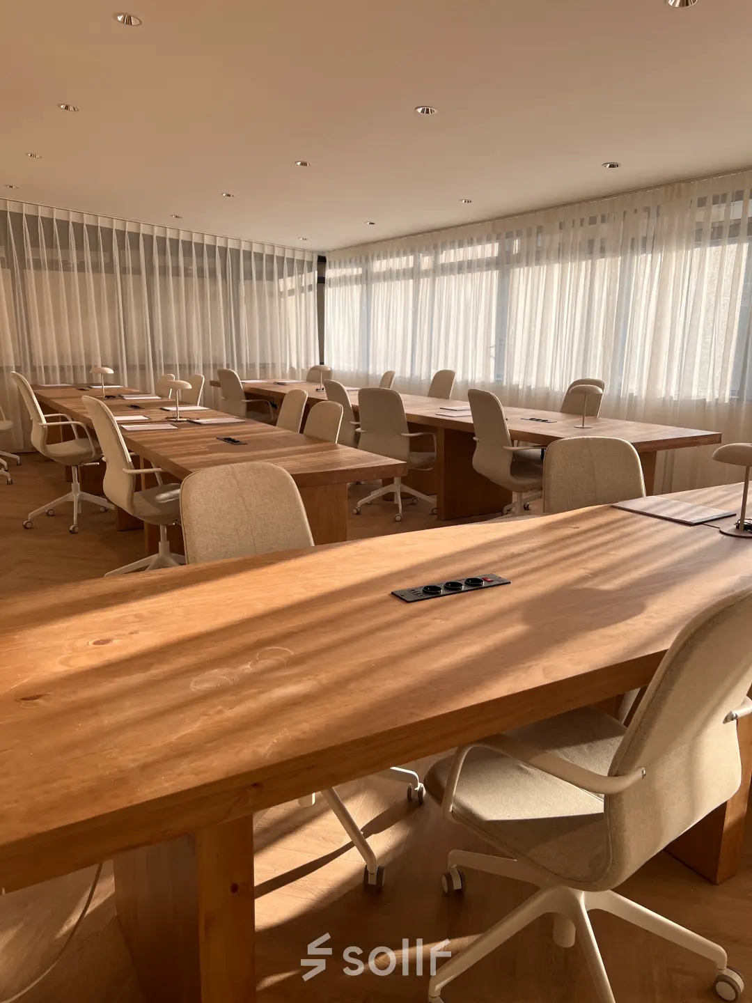 Lichte kantoorruimte in Den Haag Centrum met houten tafels en bureaustoelen, ideaal voor flexwerken of vergaderingen.