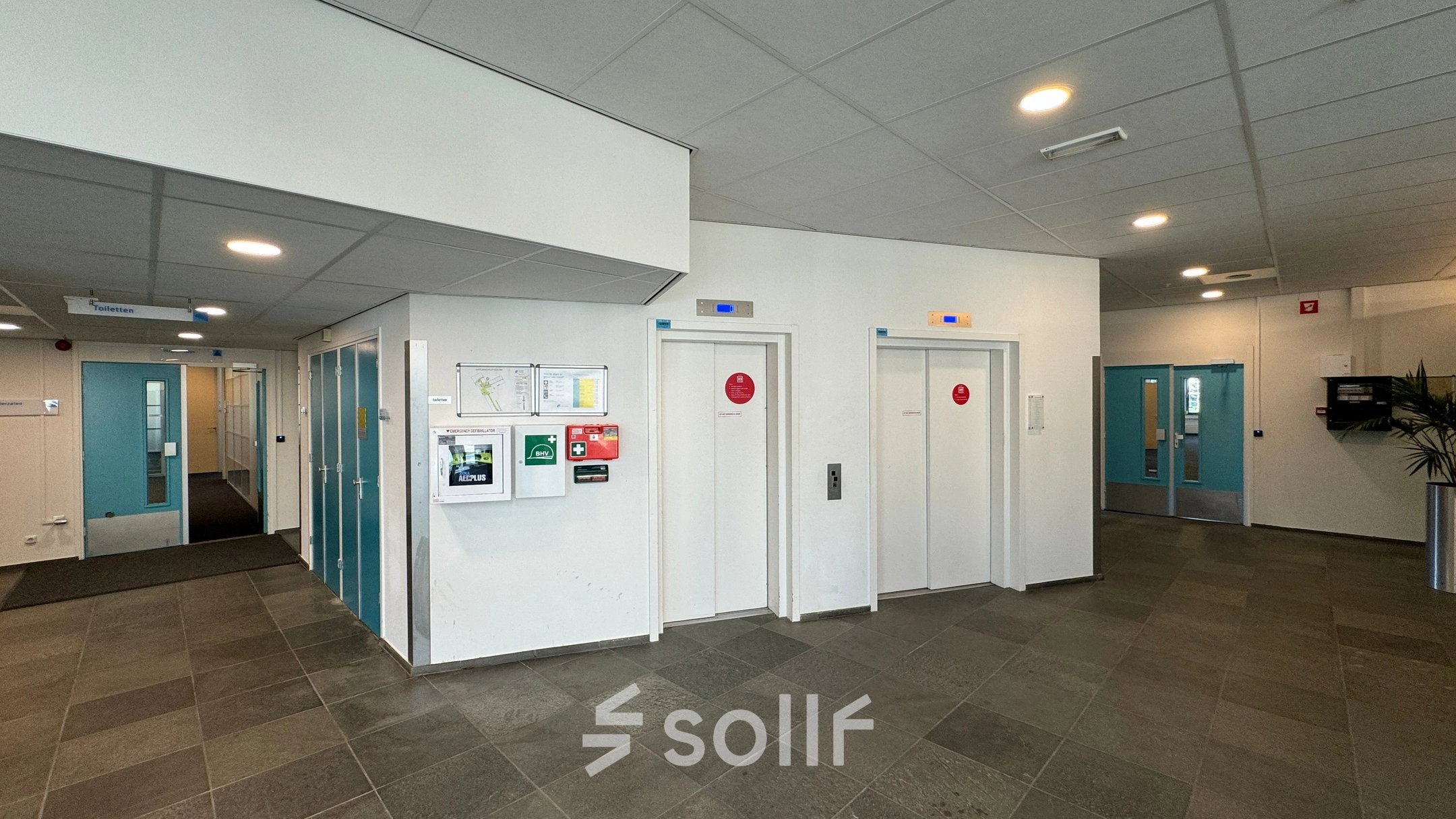 Ingang van het kantoorpand op Platinaweg 10 in Den Haag Escamp, met liften en heldere muren. Perfecte locatie voor kantoorruimte huren.