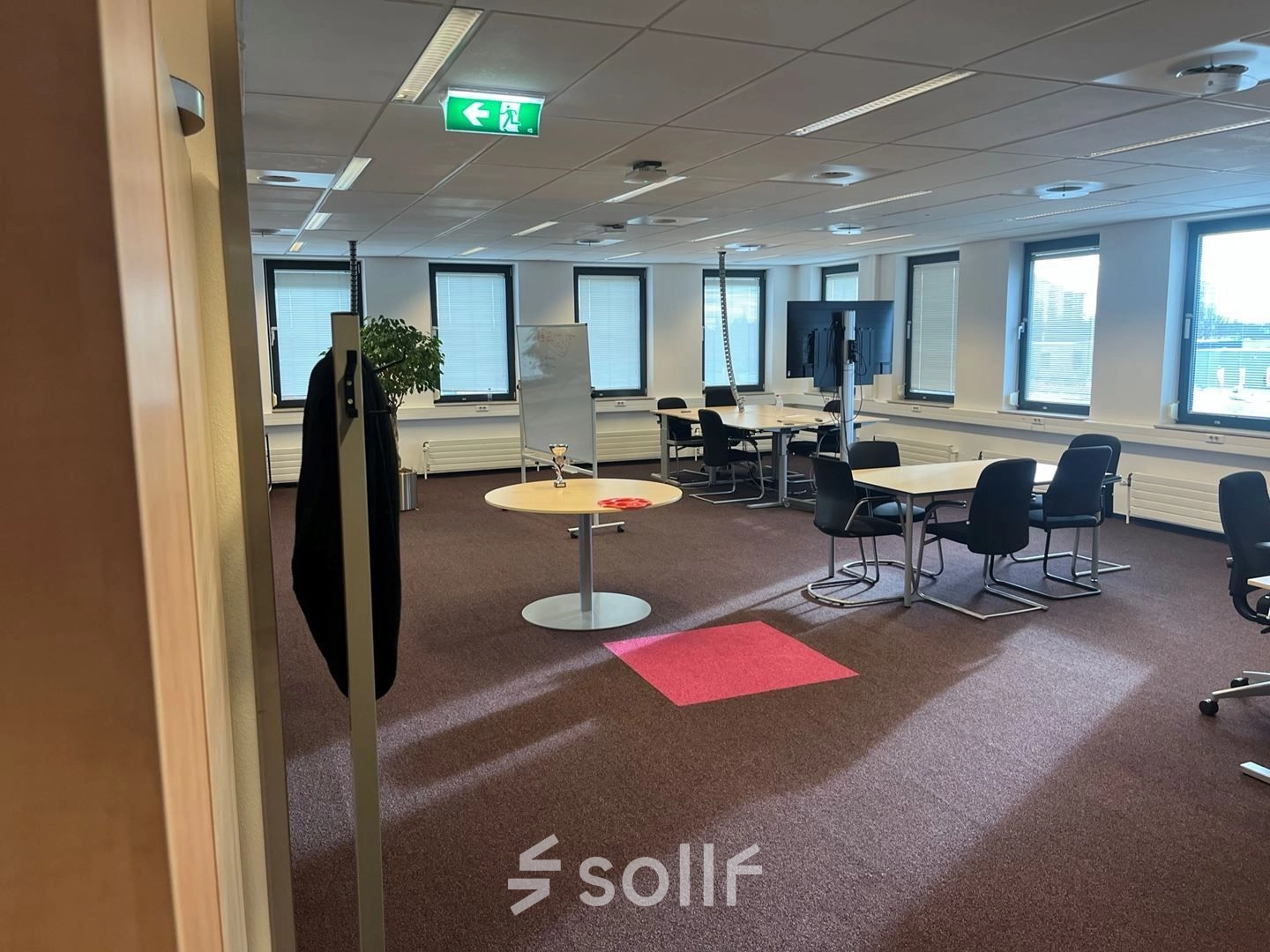 Kantoorruimte in Den Haag Escamp op Platinaweg 10 met grote ramen, een flip-over en meerdere bureau's met stoelen, ideaal voor huren.